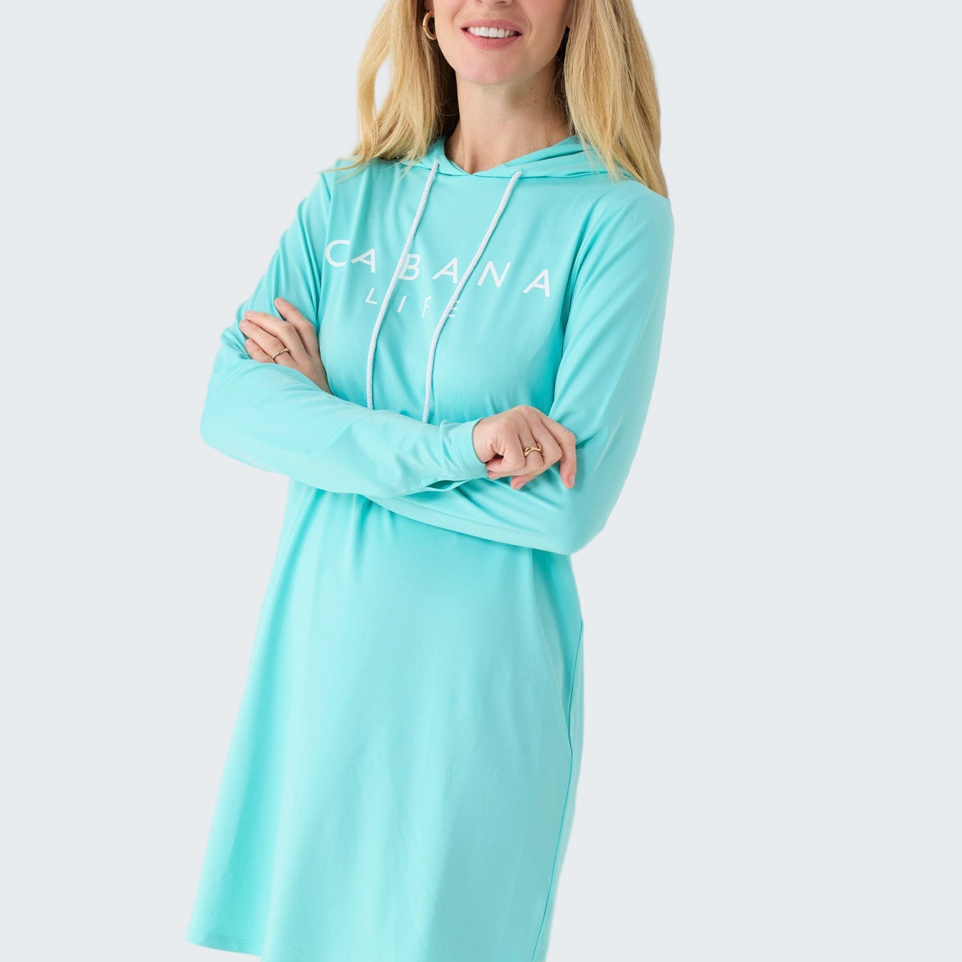 Woman wearing a light blue hoodie dress with 'Caravana' branding on a white background