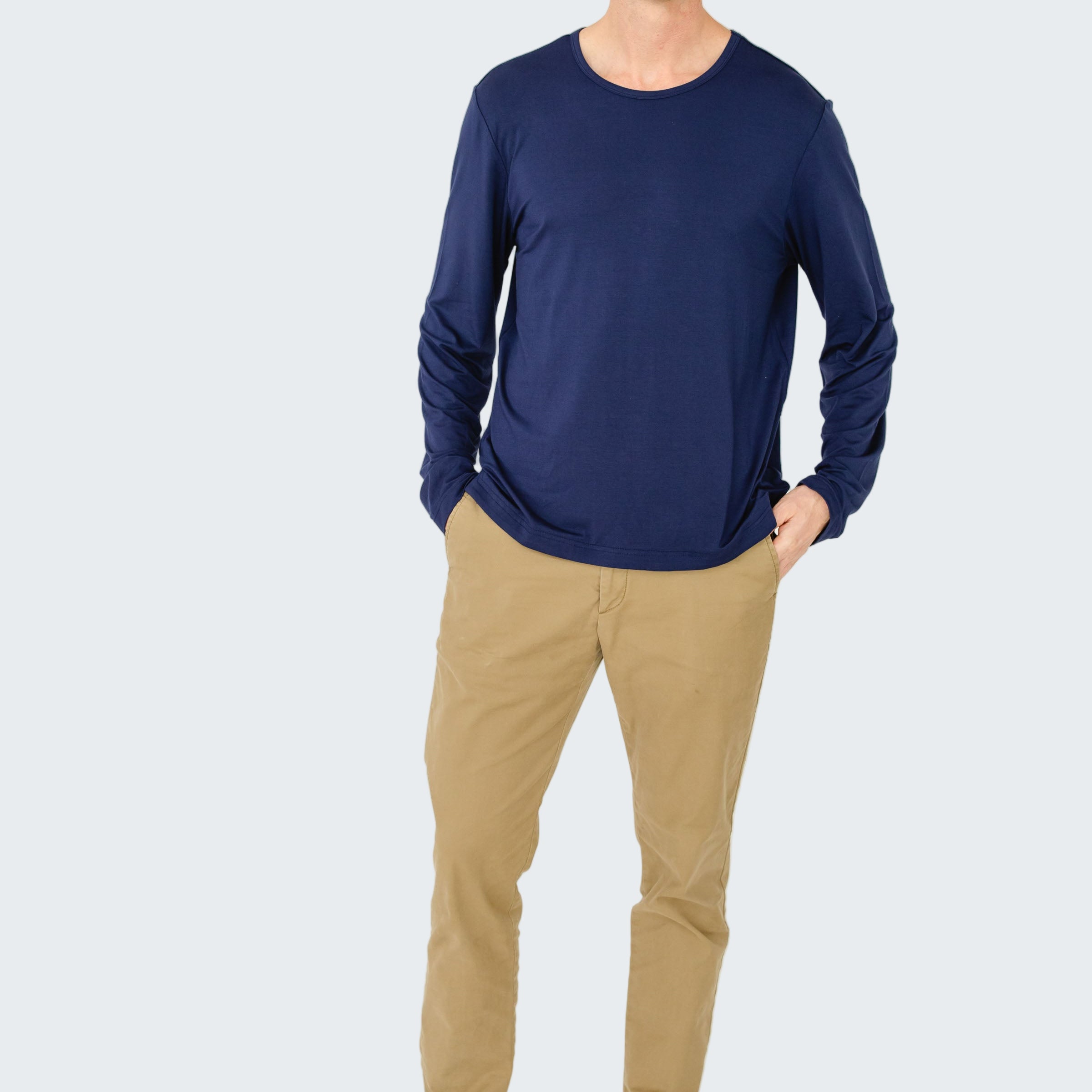 Man wearing a blue long-sleeve shirt and beige pants on a white background