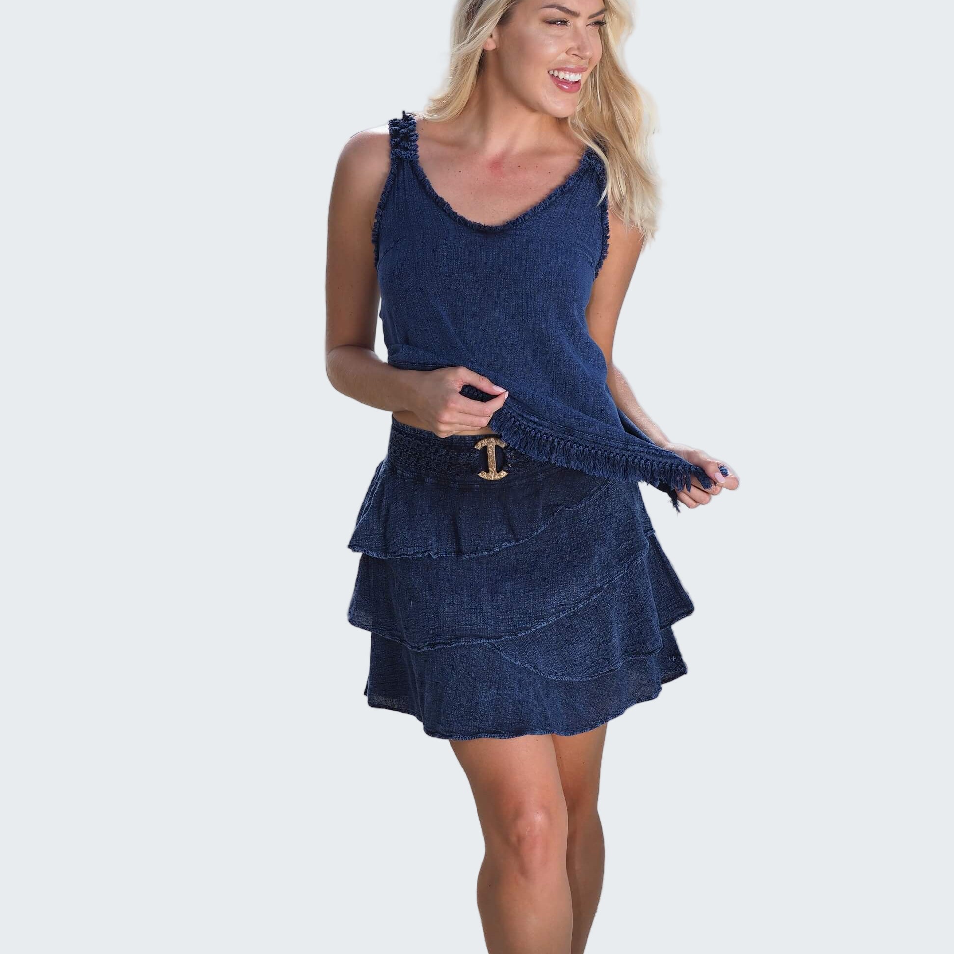 Woman in a blue dress standing on a beach with water in the background