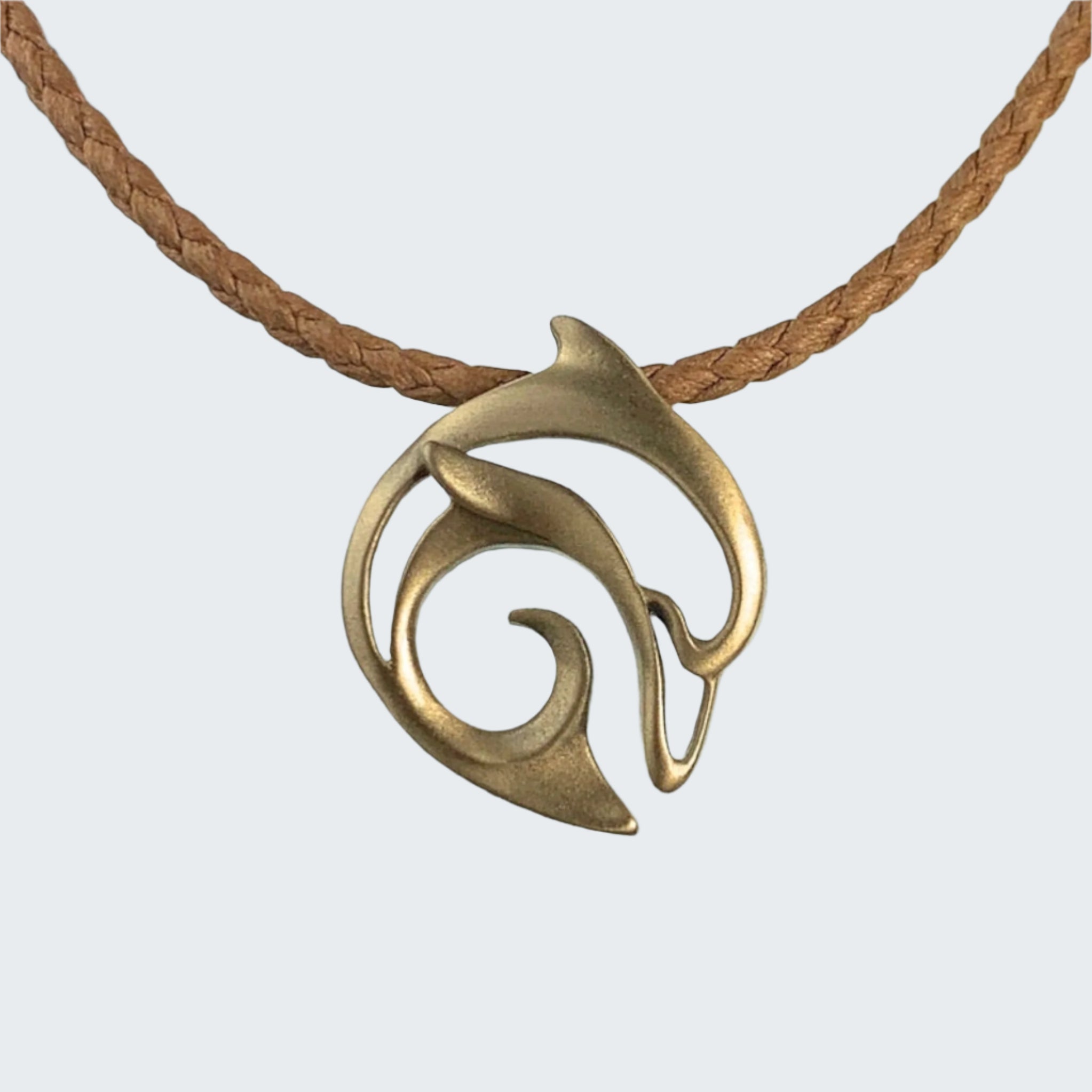 Brass pendant on a brown cord with a beach background