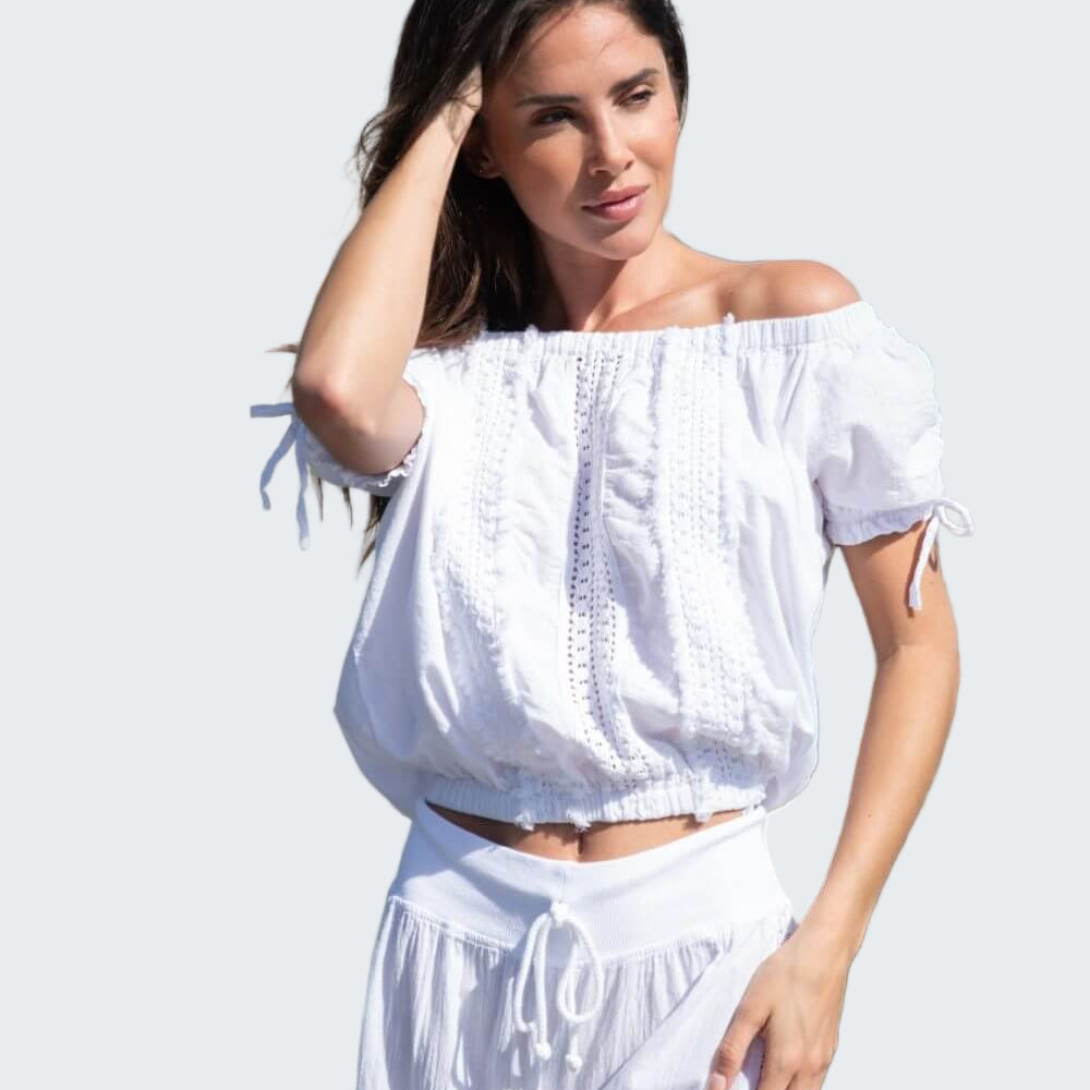 Woman in a white outfit standing by a boat on a dock.