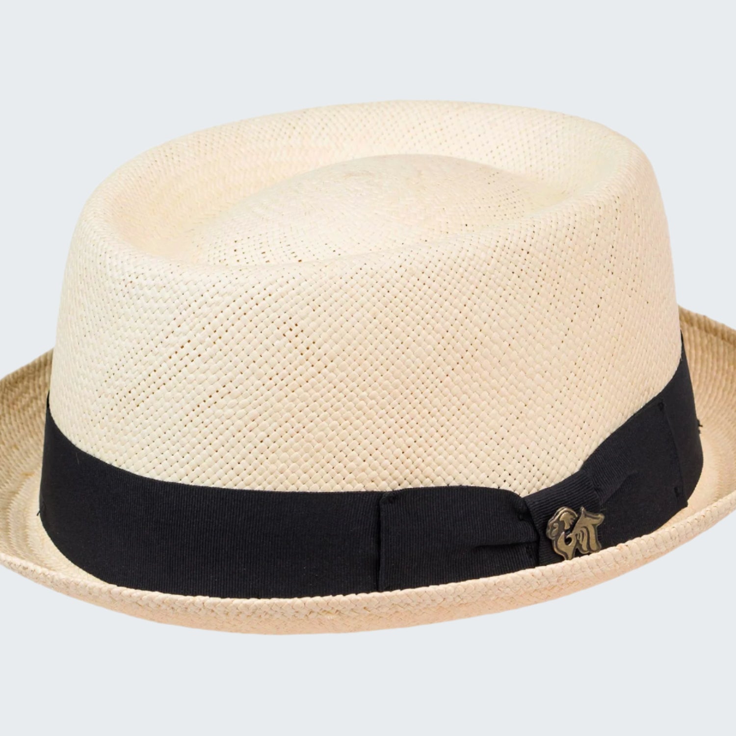 Beige straw hat with a black band and gold emblem on a white background