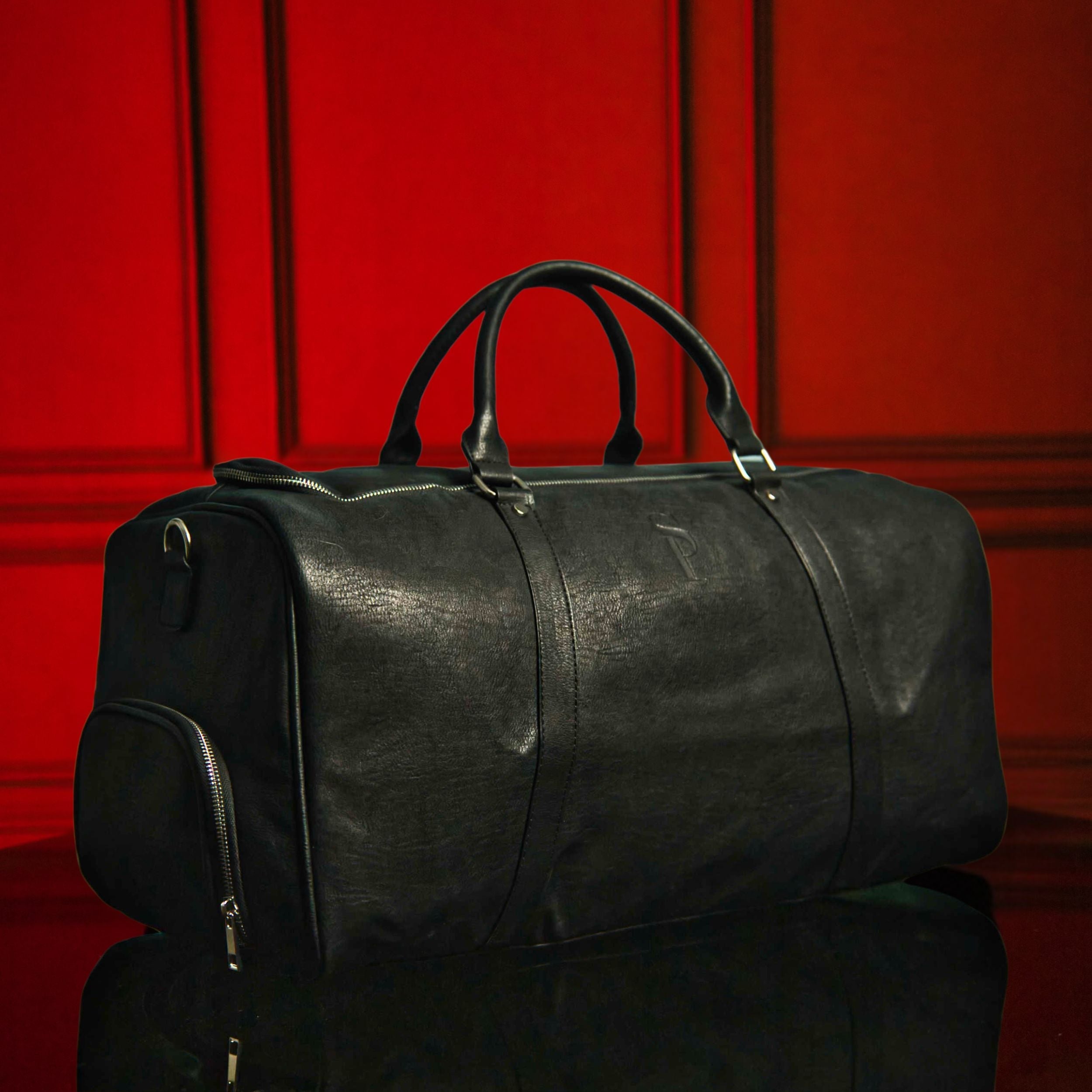 Black leather duffel bag on a red background