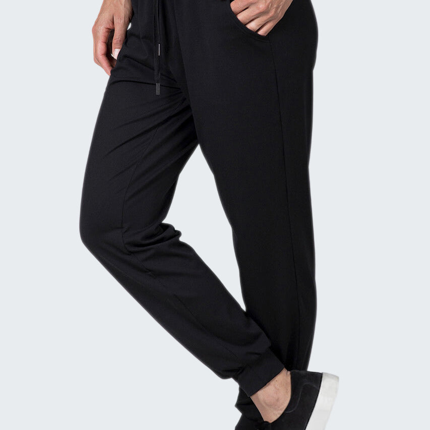 Person wearing black jogger pants and black sneakers on a white background