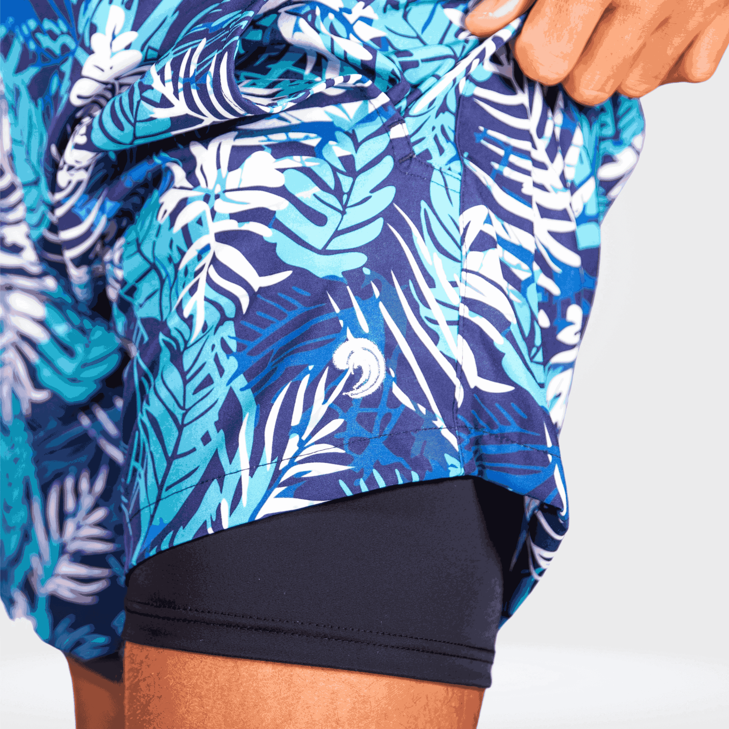 Blue and white leaf-patterned cover-up being adjusted by a hand on a white background