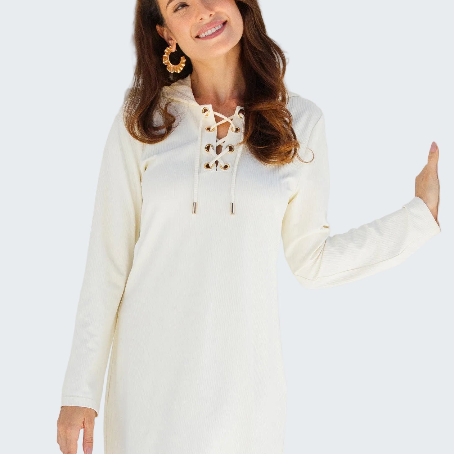 Woman wearing a white lace-up dress standing in front of a white wooden door.