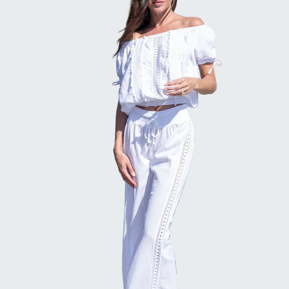 Woman in a white outfit standing by a marina with boats in the background