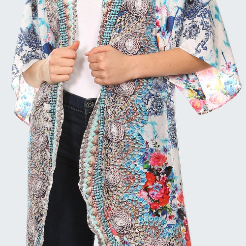 Woman wearing a colorful kimono-style jacket with floral and abstract patterns on a white background
