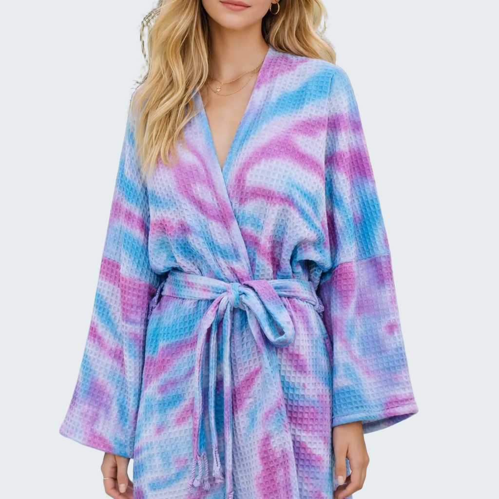 Woman wearing a colorful tie-dye robe by a poolside.