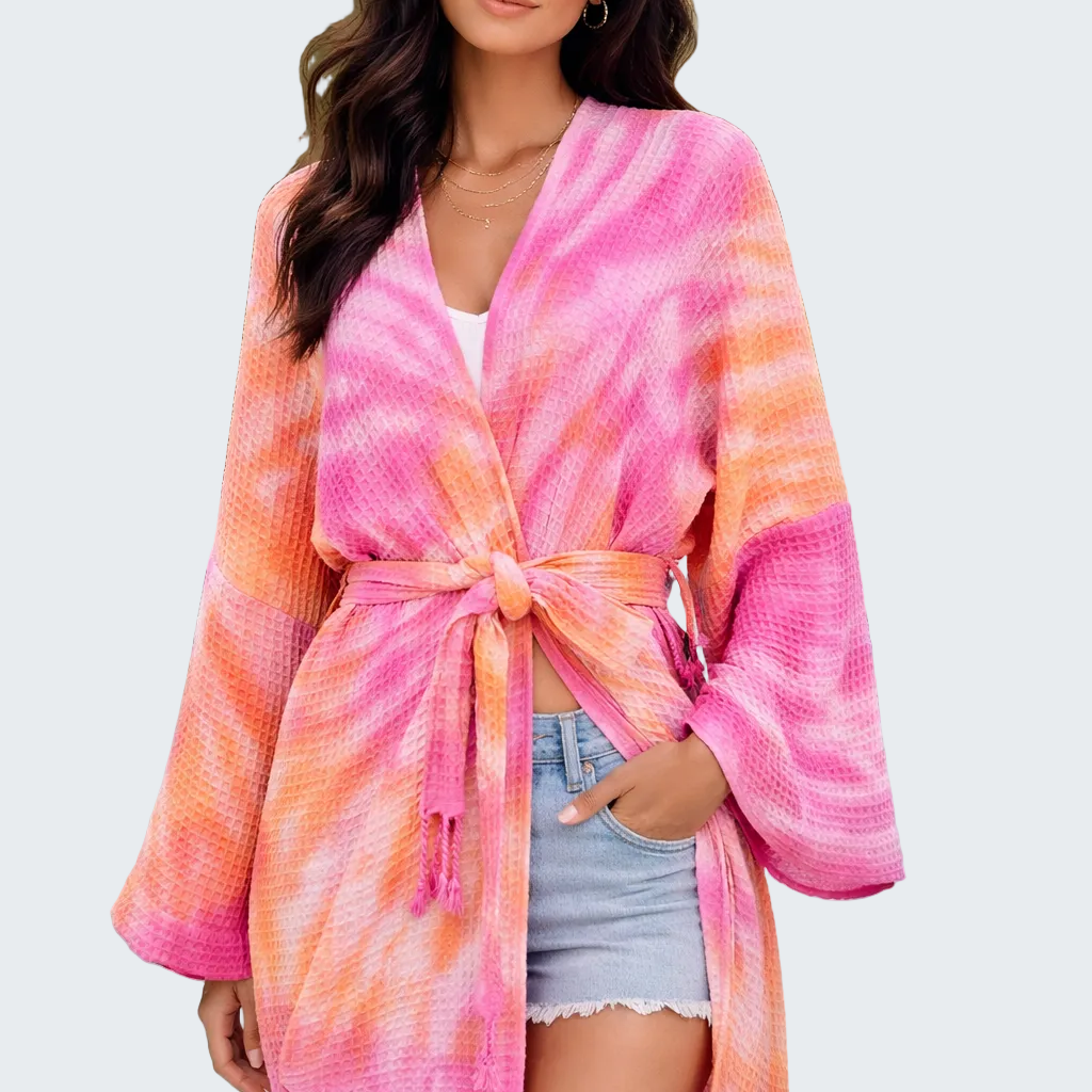 Woman wearing a pink and orange tie-dye kimono by a poolside.