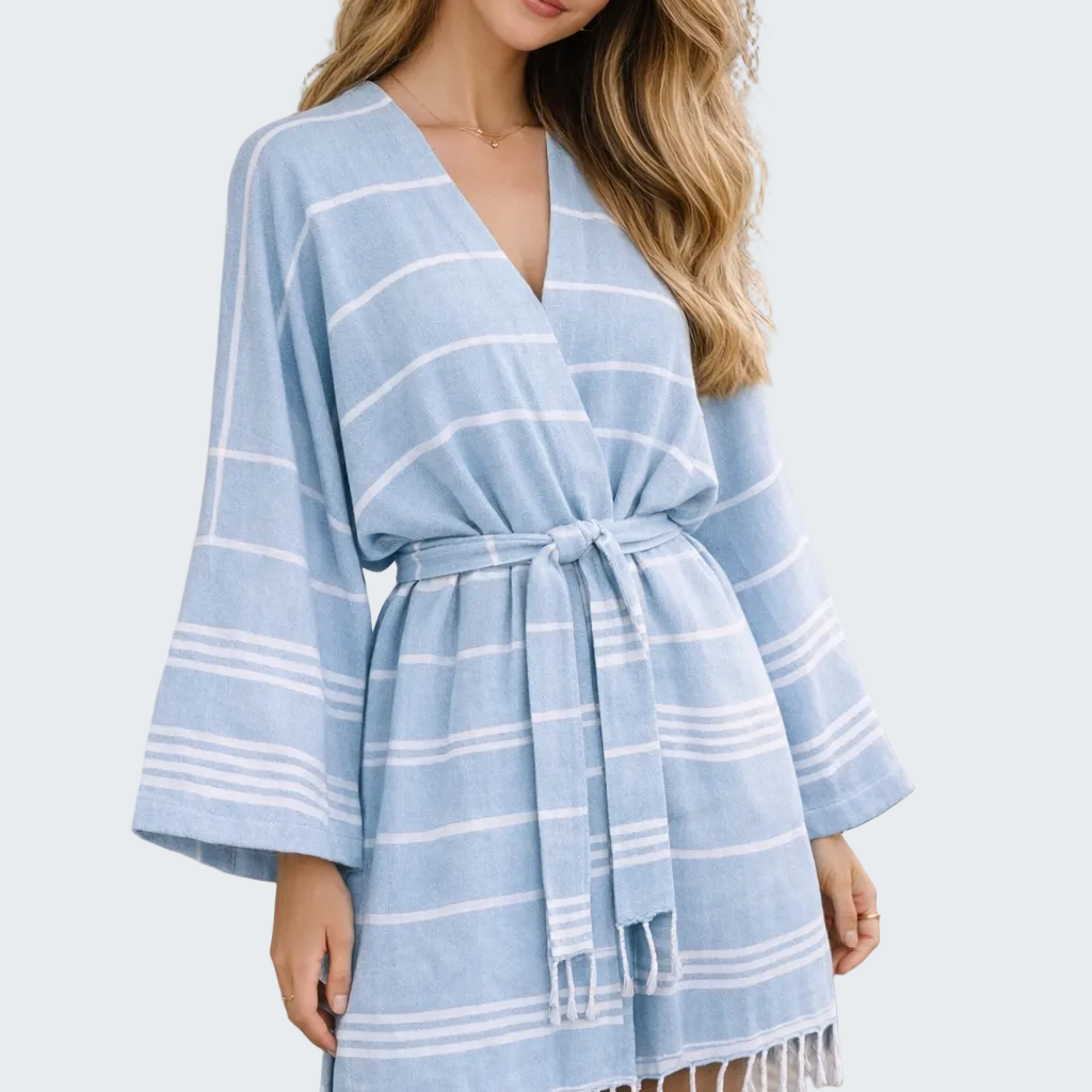 Woman wearing a blue striped dress with fringe details outdoors.