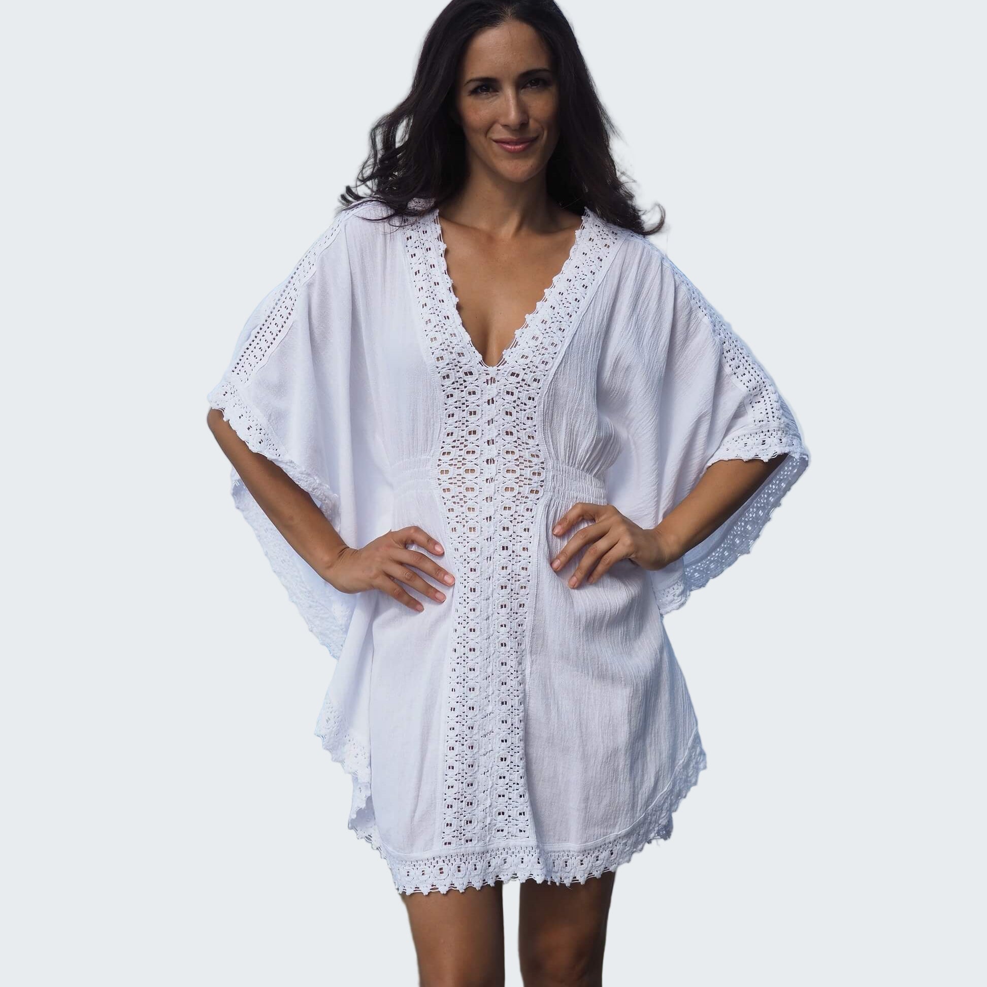 Woman wearing a white lace dress standing by a waterfront with a city skyline in the background