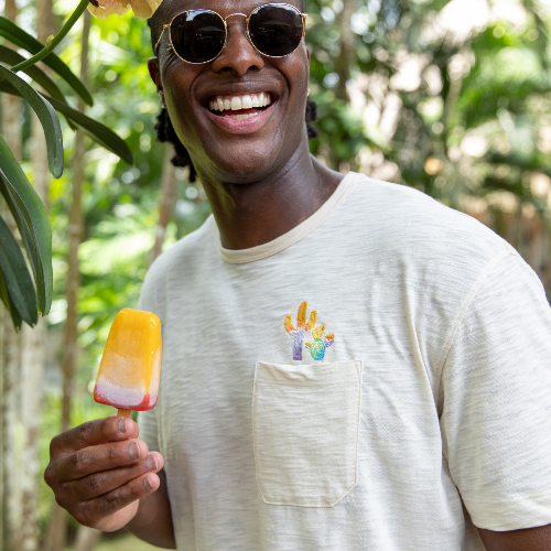 Man holding a popsicle with a tropical background