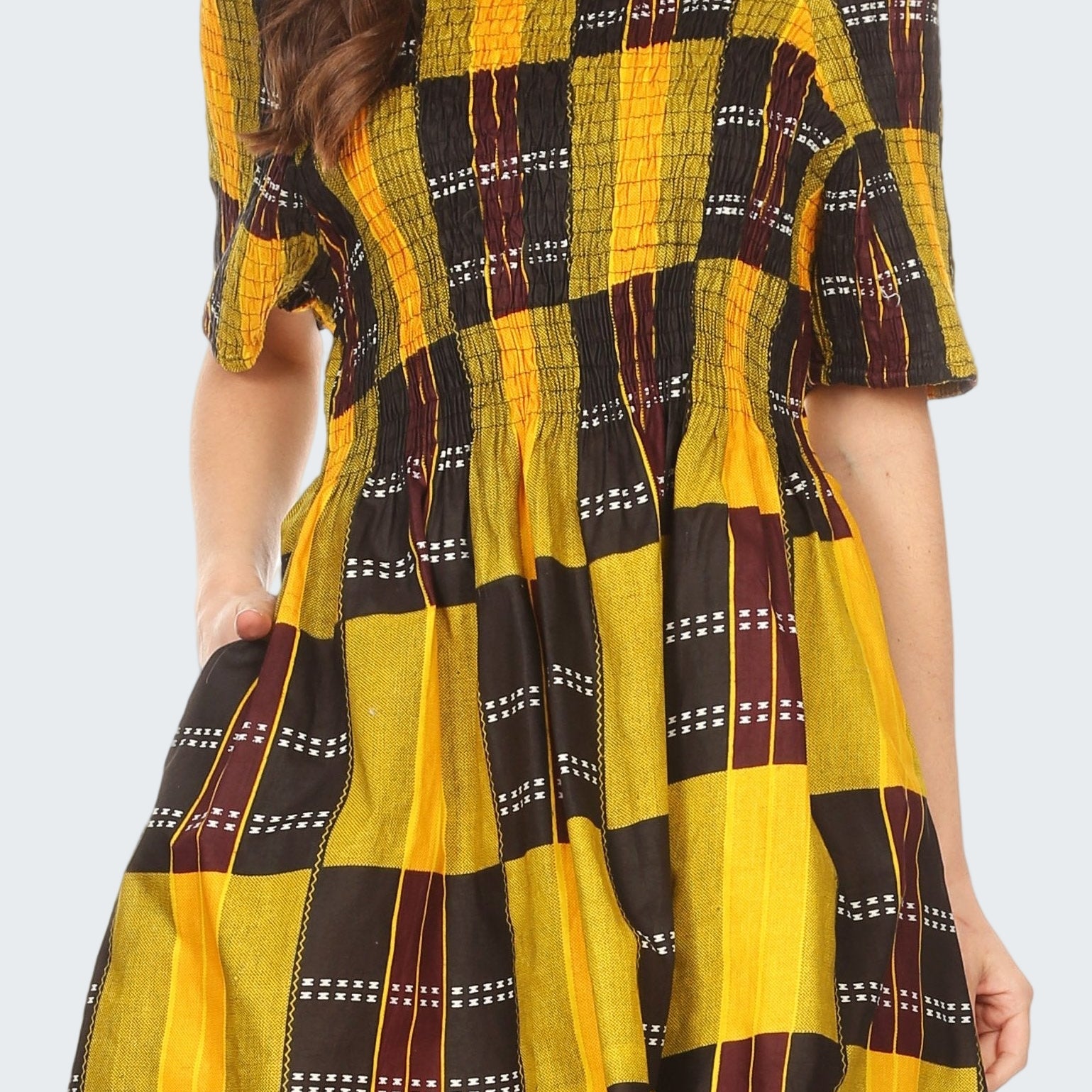 Woman wearing a yellow and black checkered dress with off-shoulder sleeves.