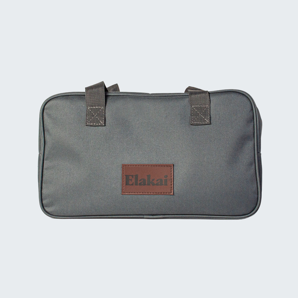 Gray bag with brown leather patch and 'Elakai' branding on a white background