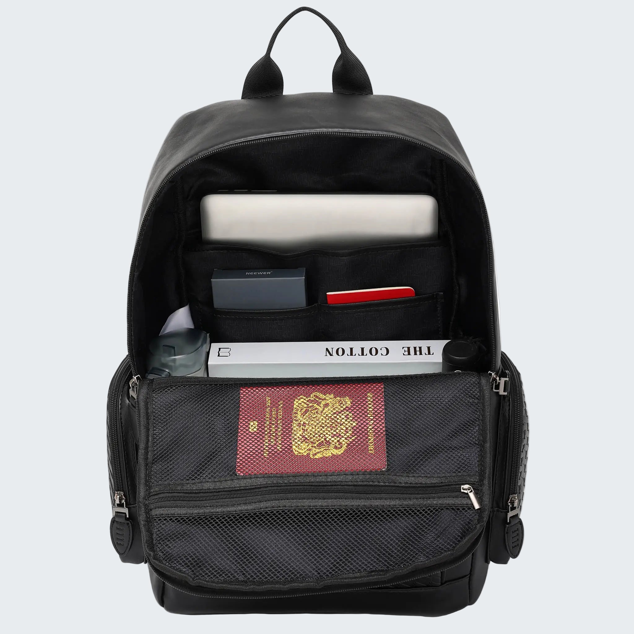 Black backpack with items including a passport on a white background