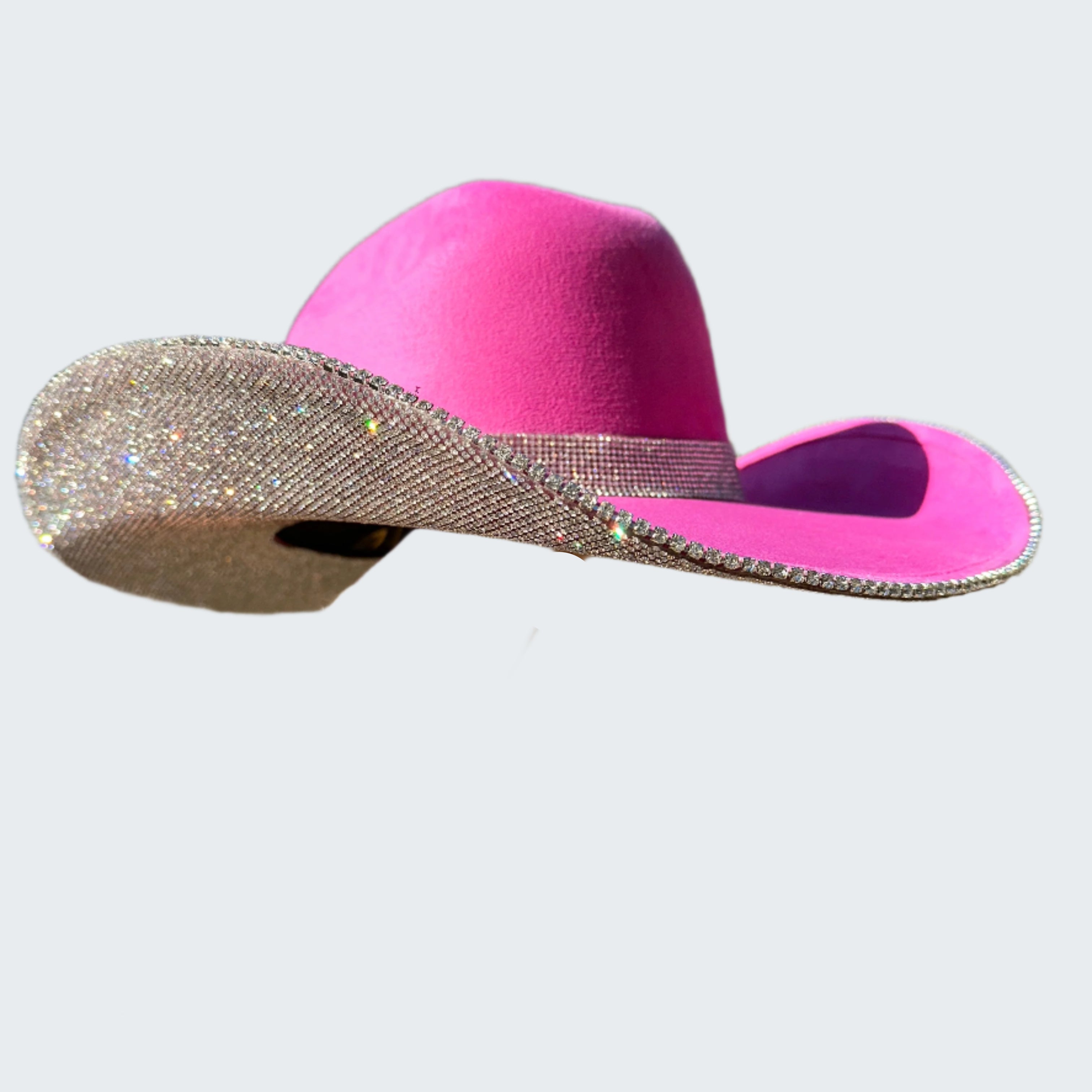 Pink cowboy hat with a silver band held by a person outdoors.