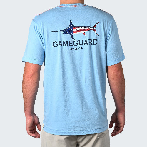Light blue t-shirt with 'Gameguard' logo and American flag design on the back, worn by a person.