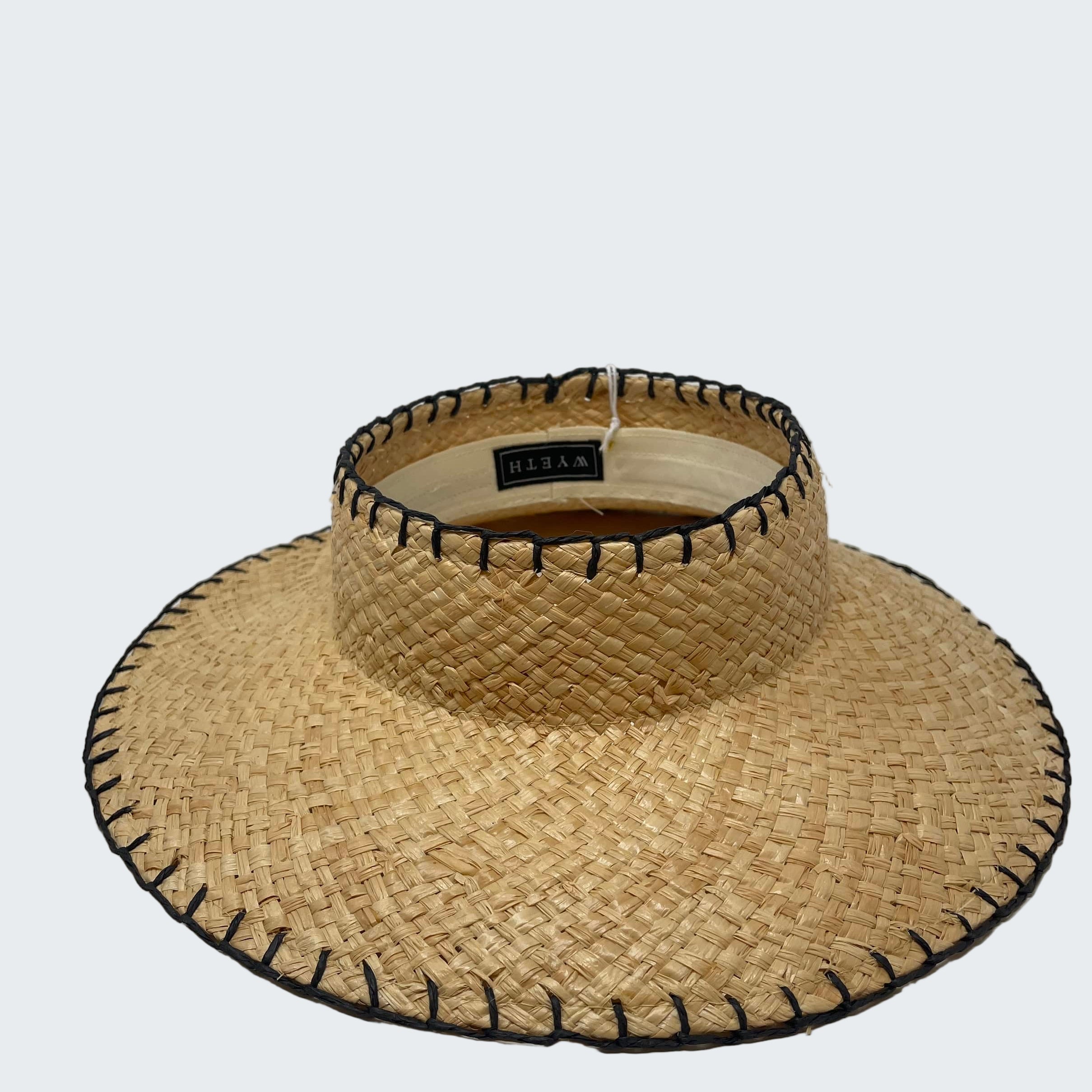 Straw visor hat with black trim on a white background
