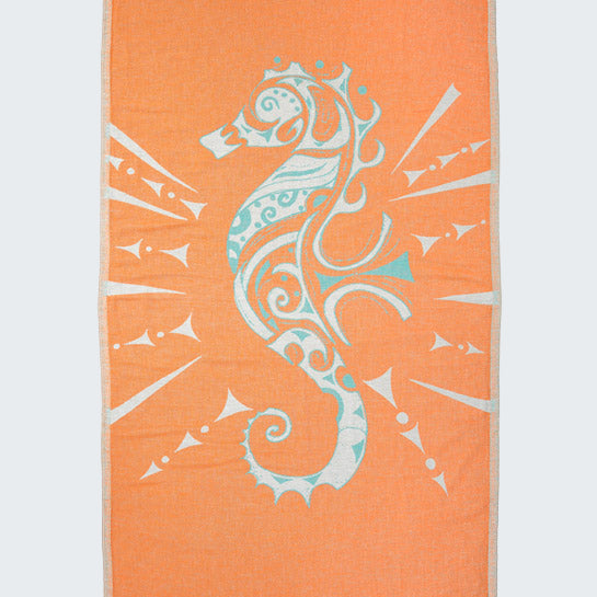 Orange beach towel with a white seahorse design on a white background
