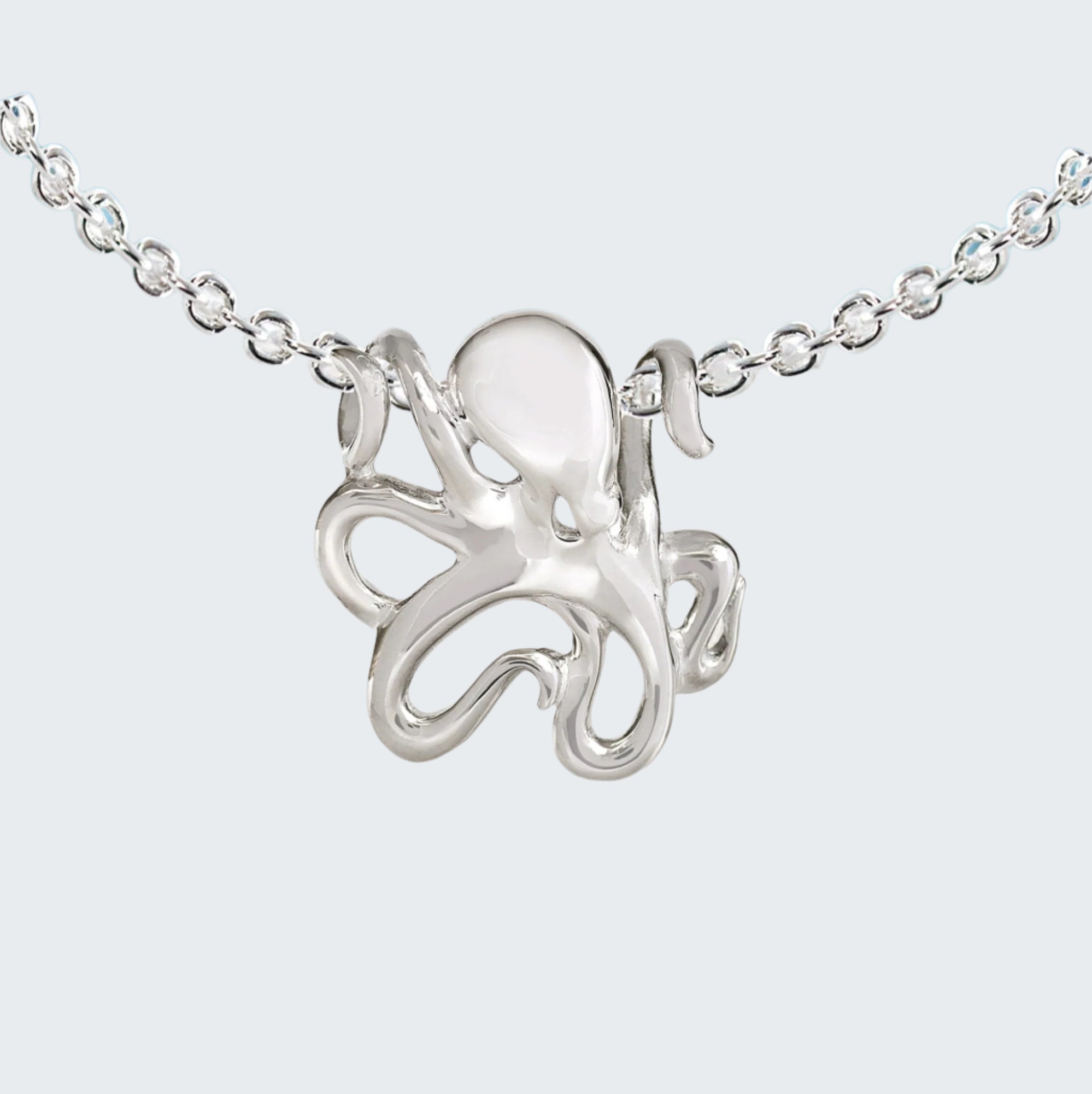 Silver octopus necklace on a chain with a beach background
