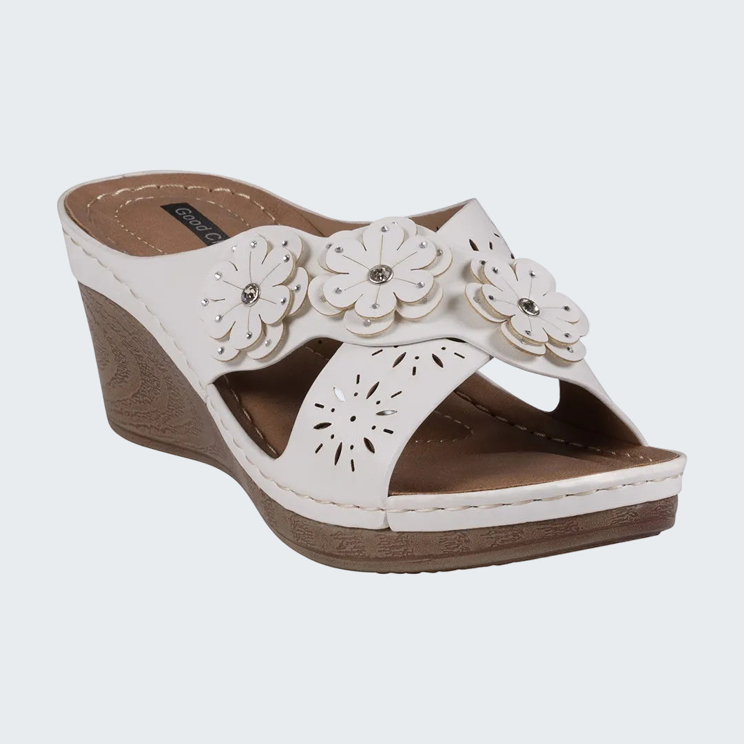 White wedge sandal with floral designs on a white background