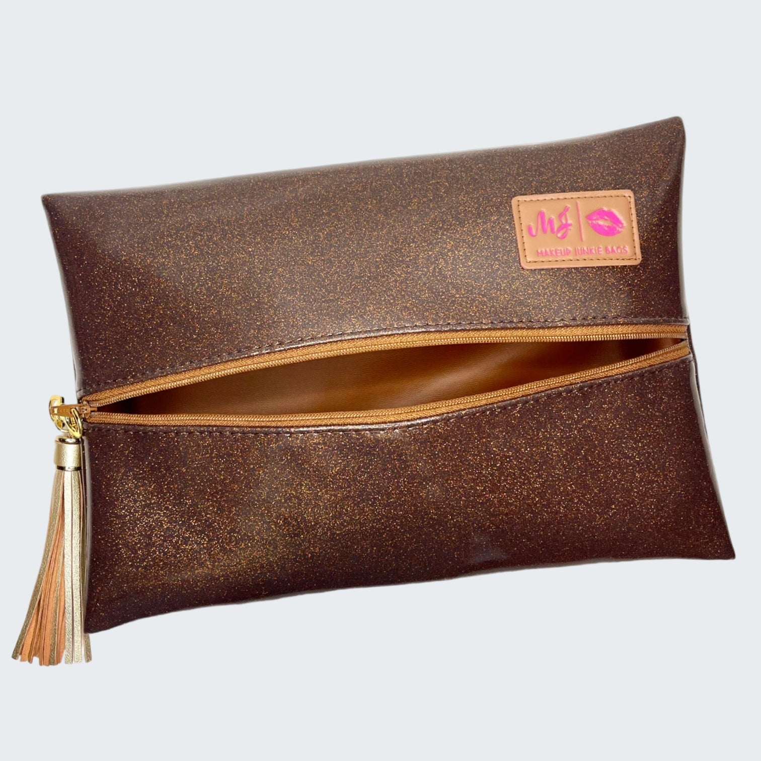 Brown clutch bag with gold tassel and visible brand logo on a white background