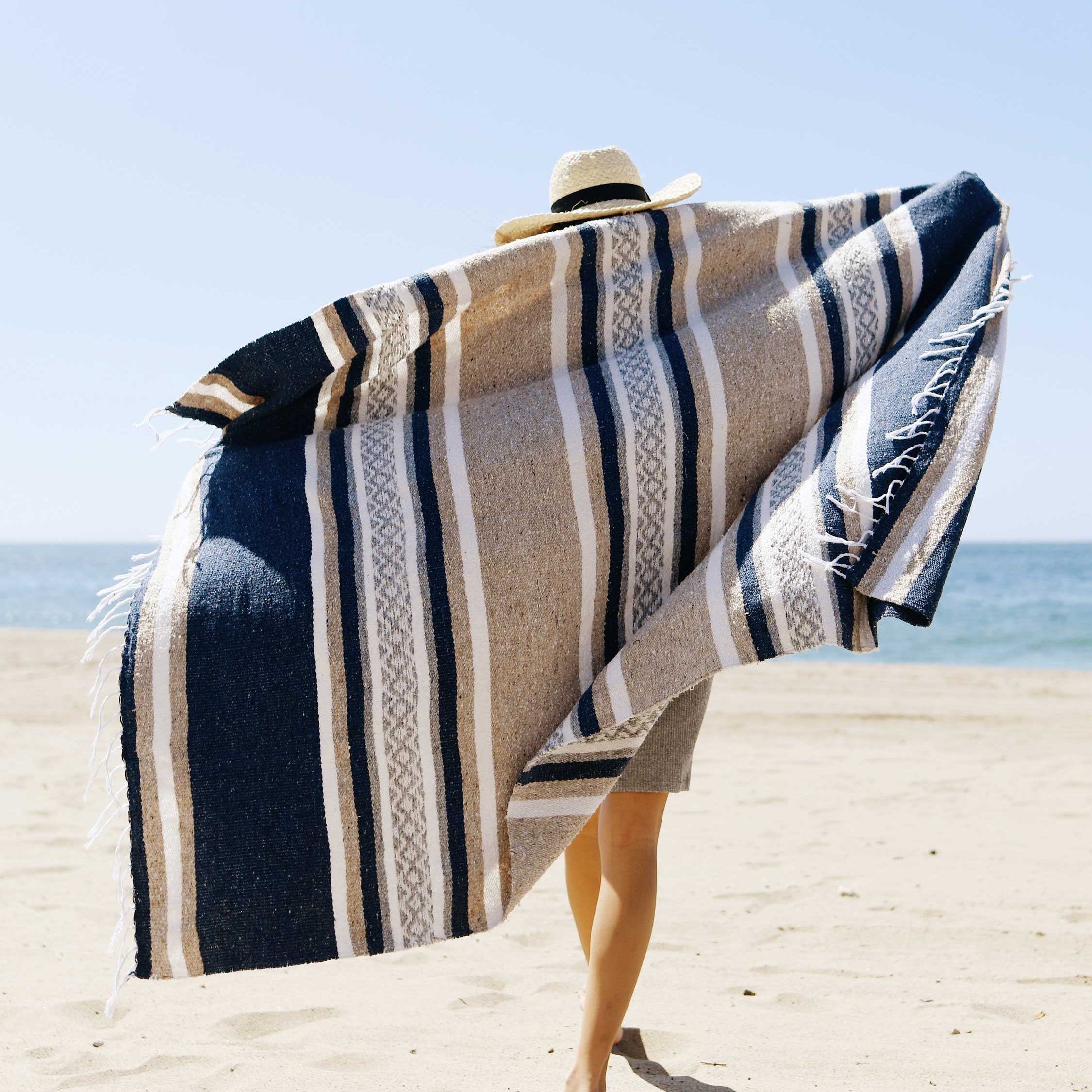 Person on a beach with a striped towel draped over their shoulders