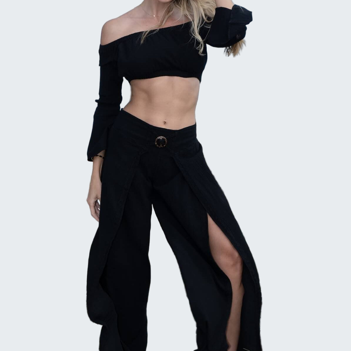 Woman in black outfit standing on a beach with palm trees in the background