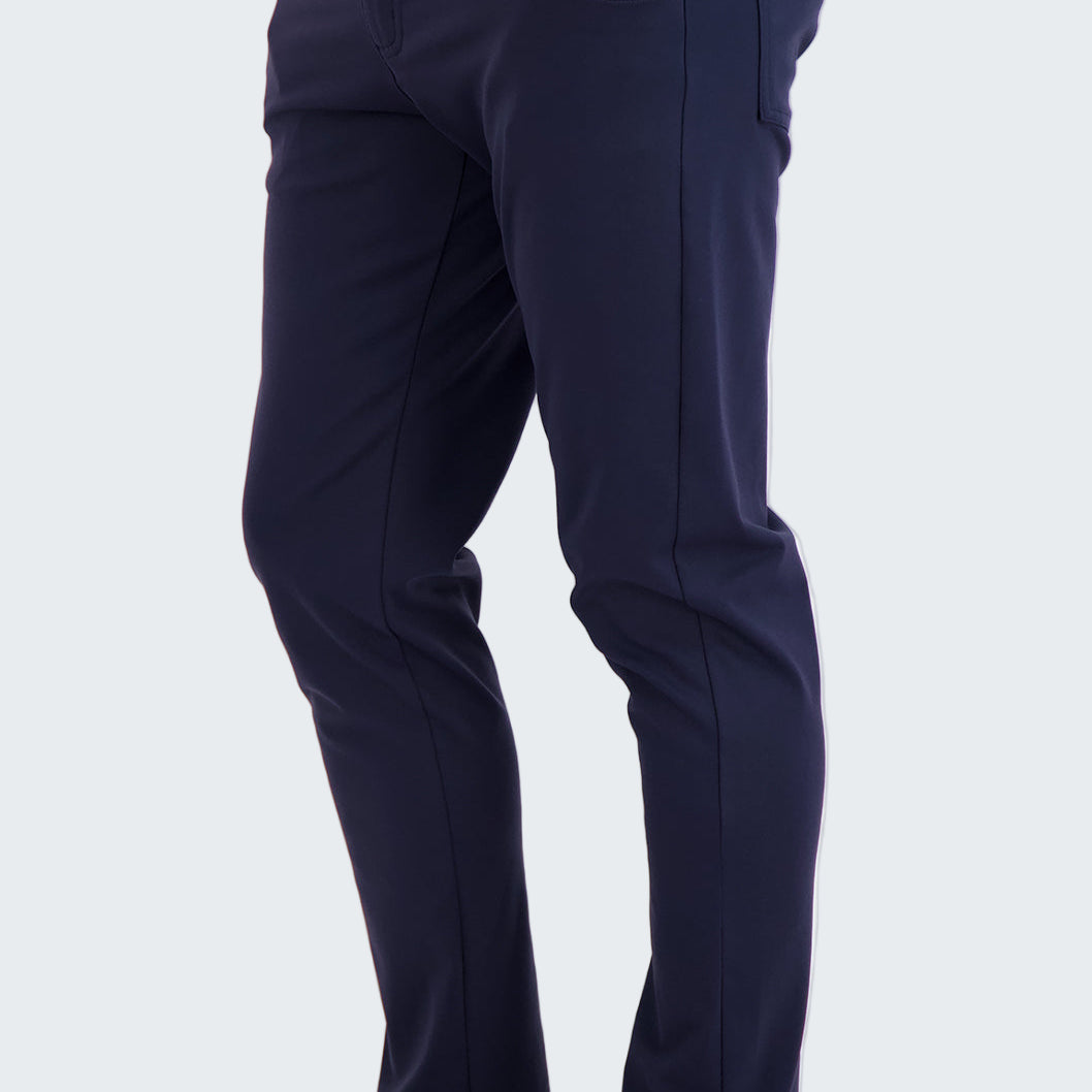 Person wearing navy pants with a white shirt and black sneakers on a white background