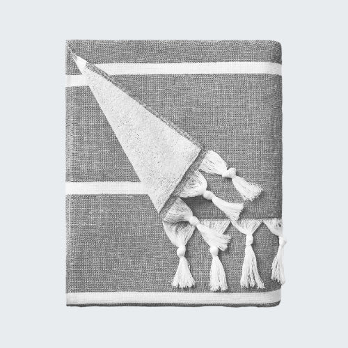 Gray towel with a white geometric design and tassels on a white background