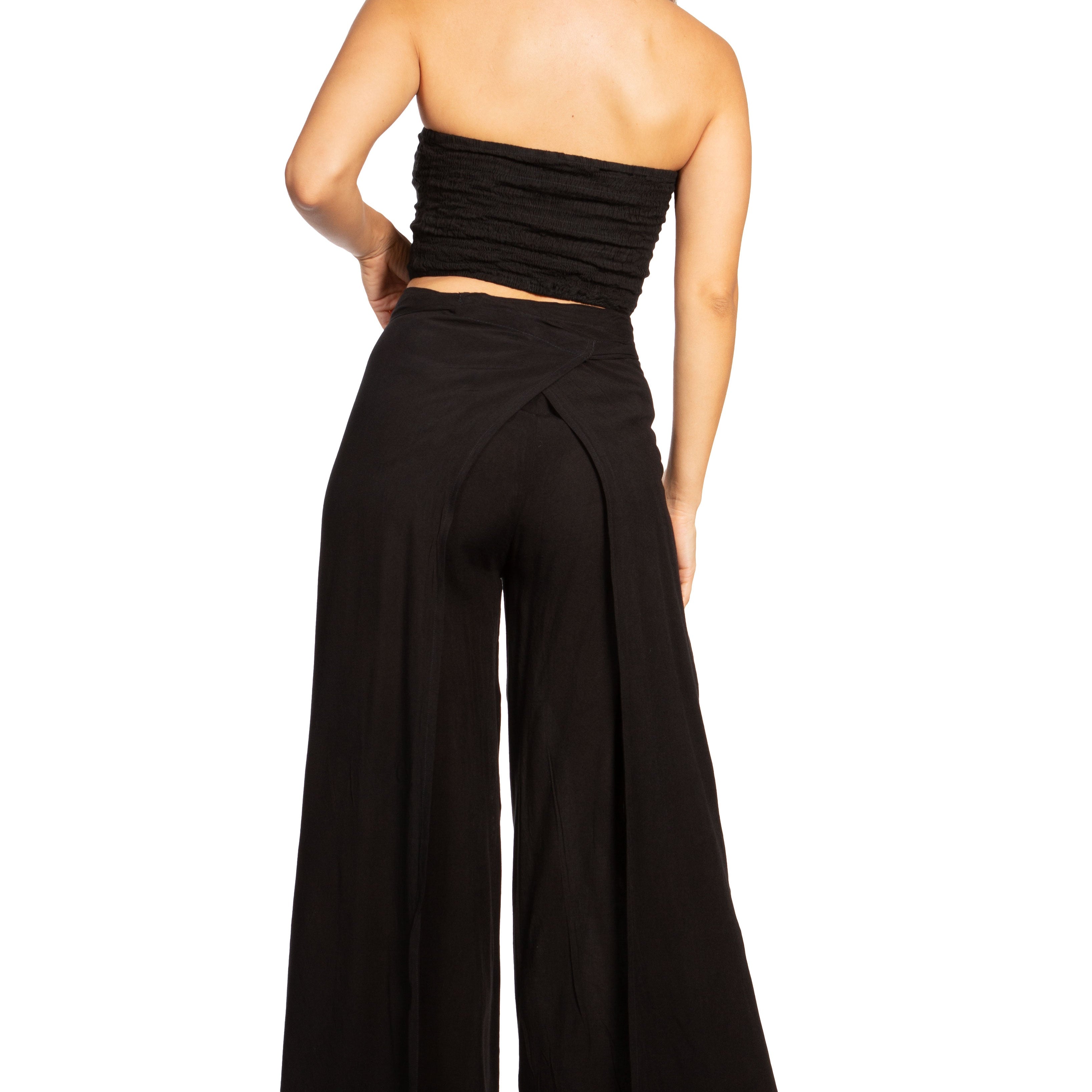 Woman wearing a black strapless top and wide-leg pants on a white background