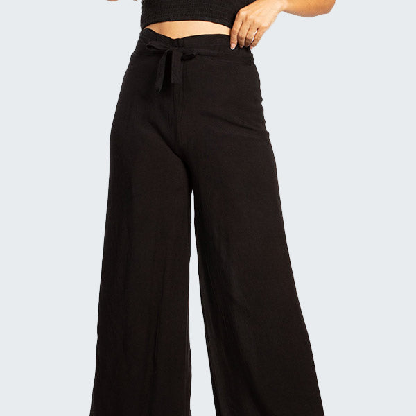 Woman wearing a black strapless top and wide-leg pants on a white background