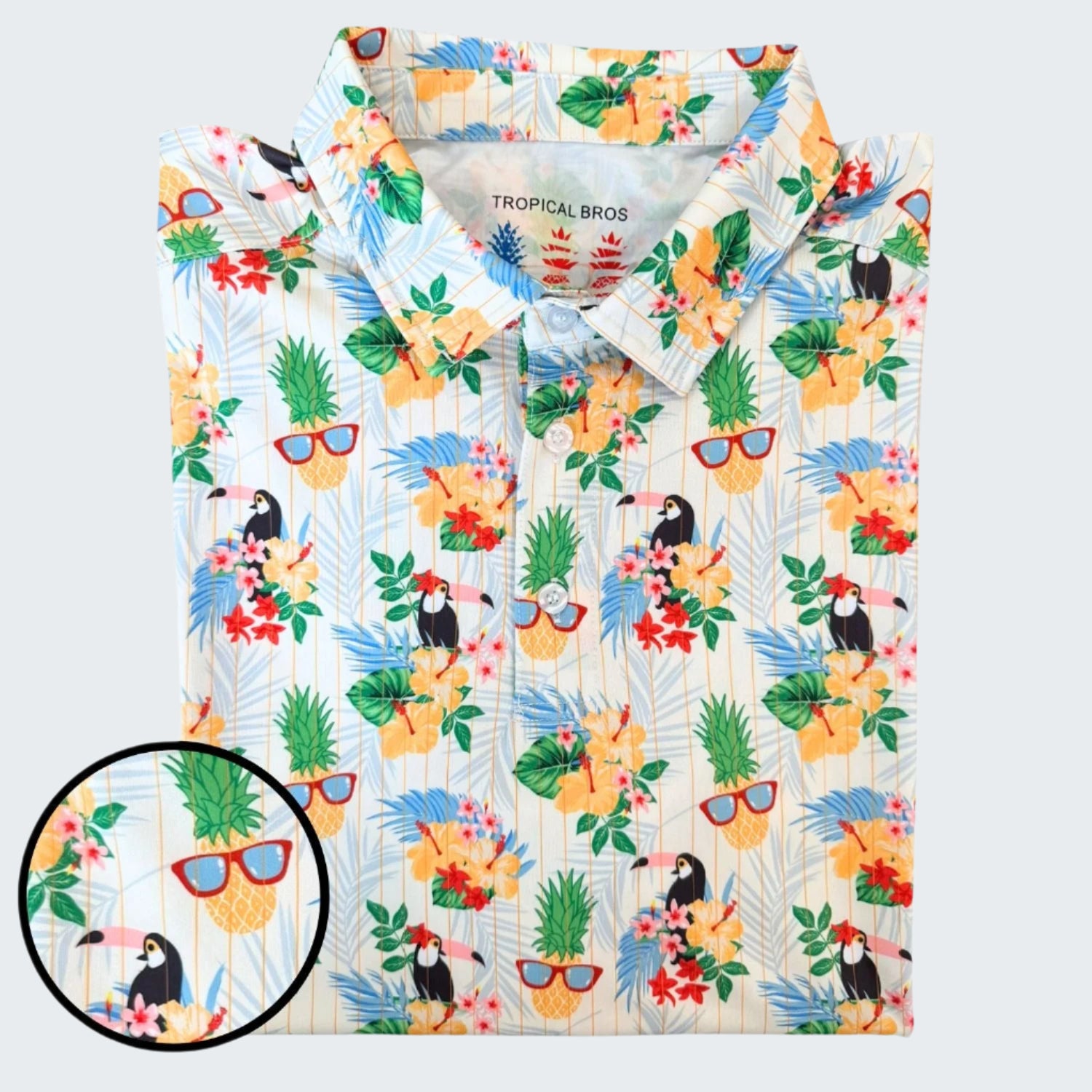 Colorful shirt with tropical pattern featuring toucans, pineapples, and flowers on a white background.