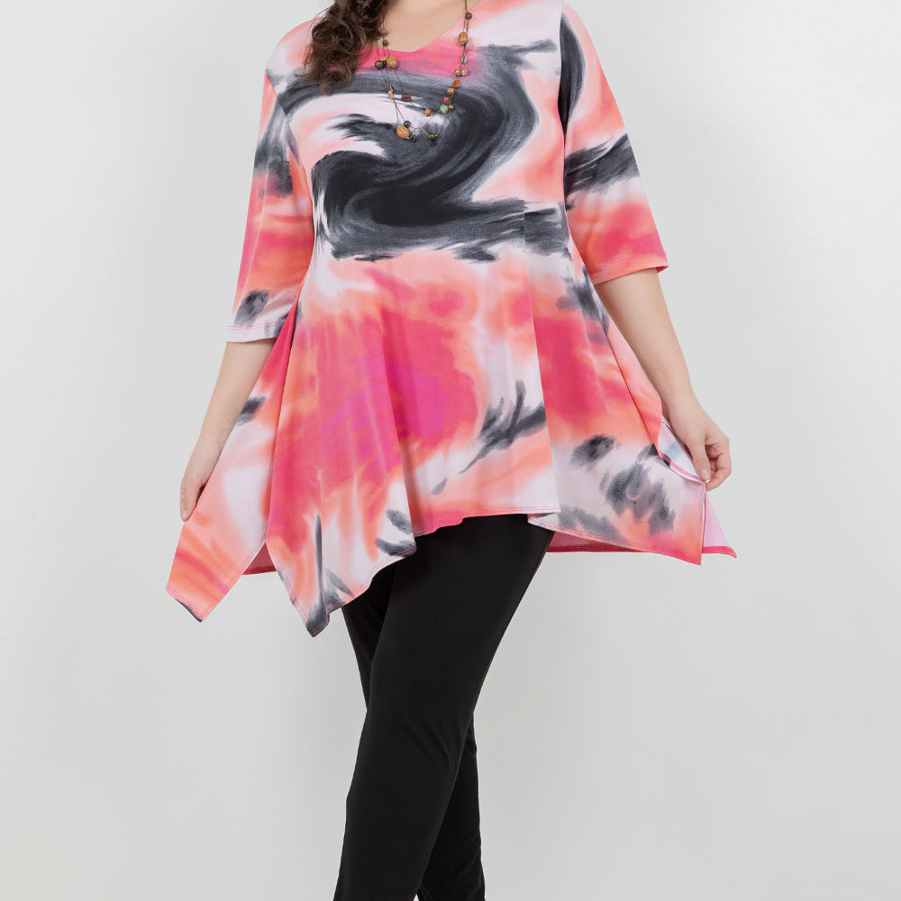 Woman wearing a colorful abstract patterned top and black pants on a white background