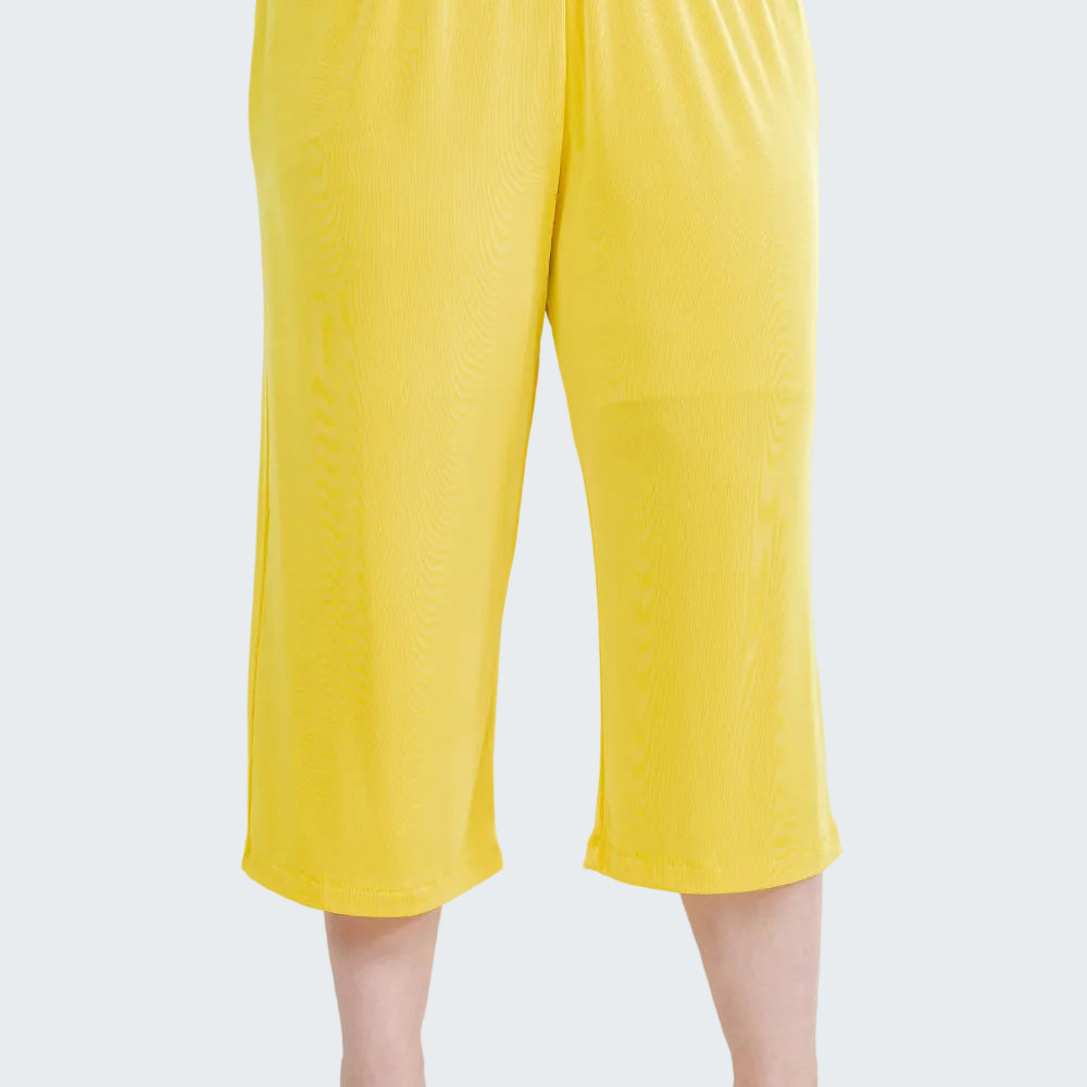 Yellow capri pants worn by a person on a white background