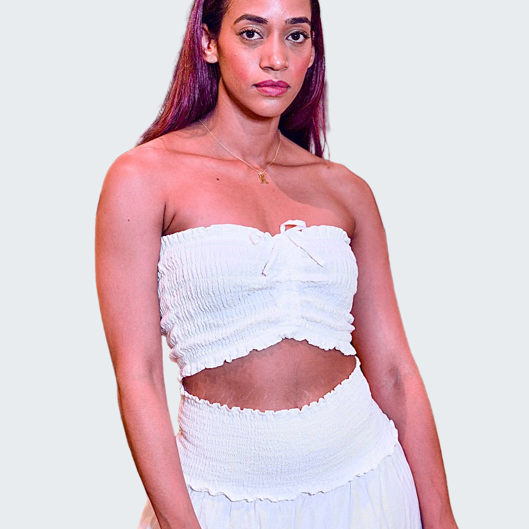 Woman wearing a white strapless top and skirt in an indoor setting