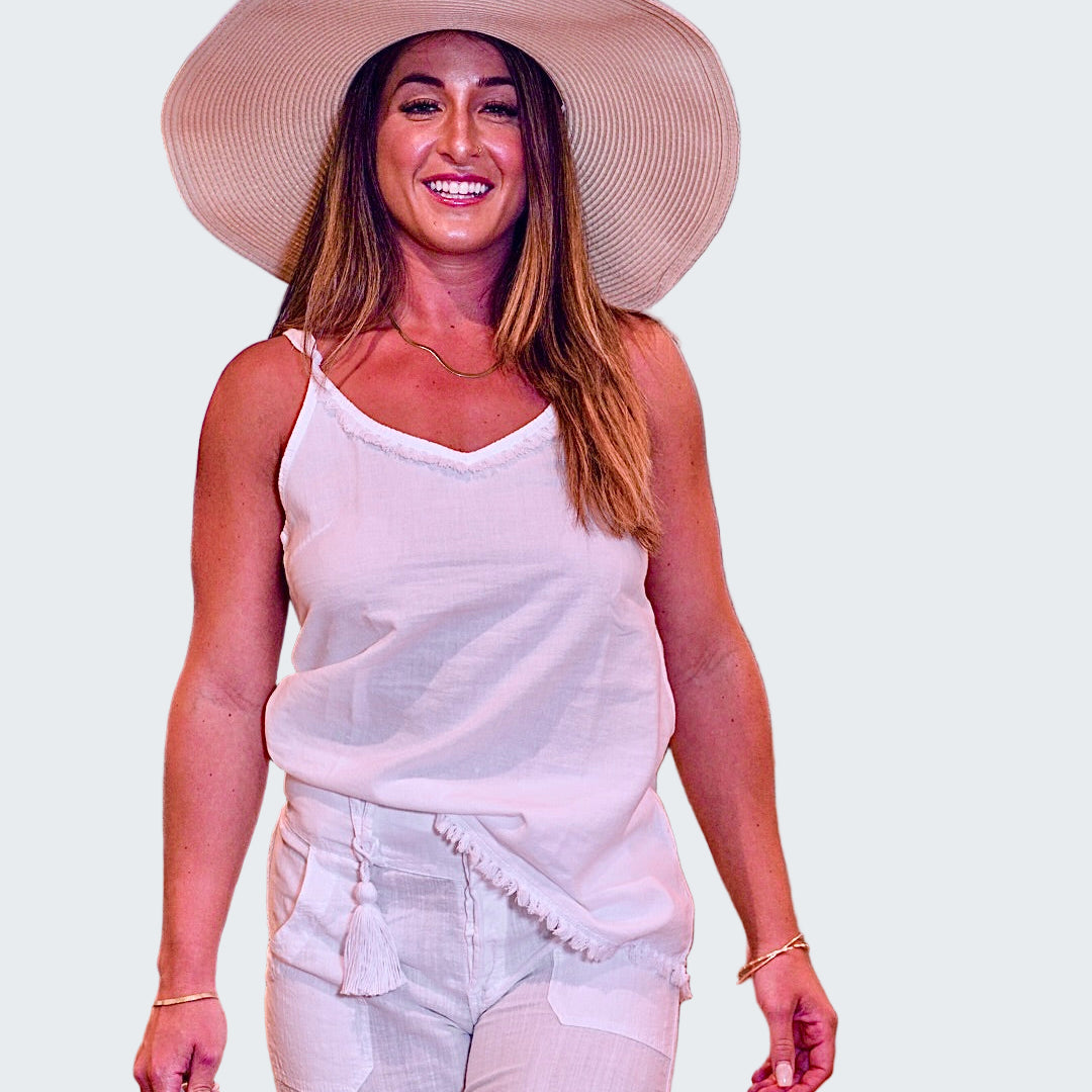 Woman in a white outfit and large hat walking indoors with blurred background