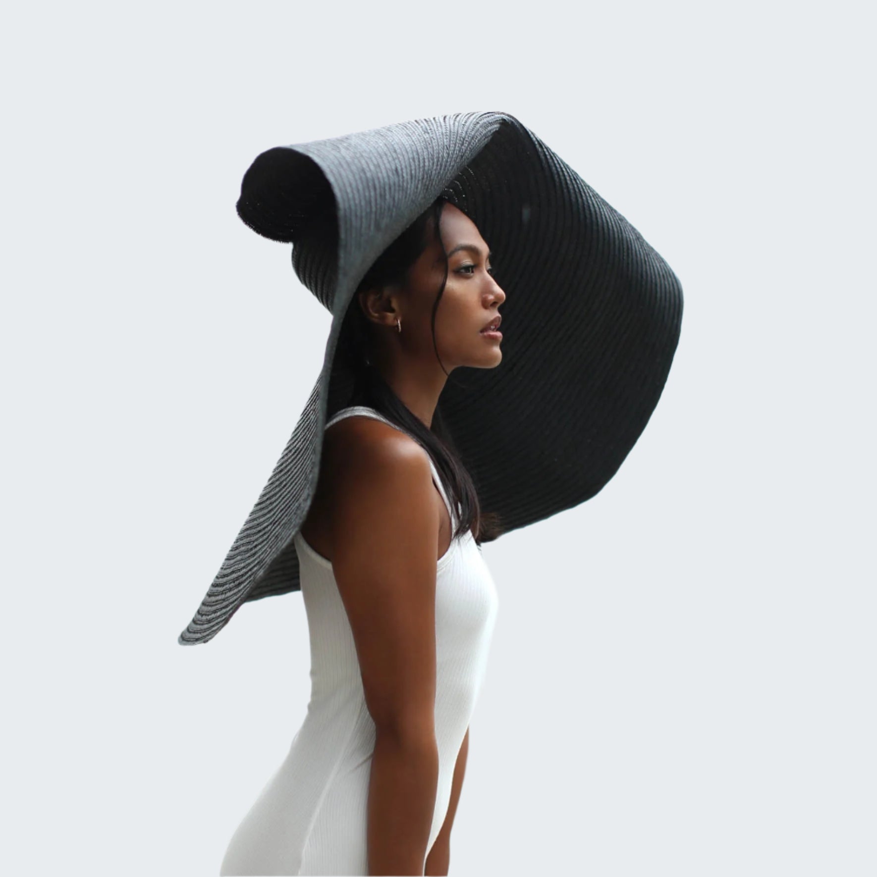 Woman wearing a large black sun hat with a blurred background