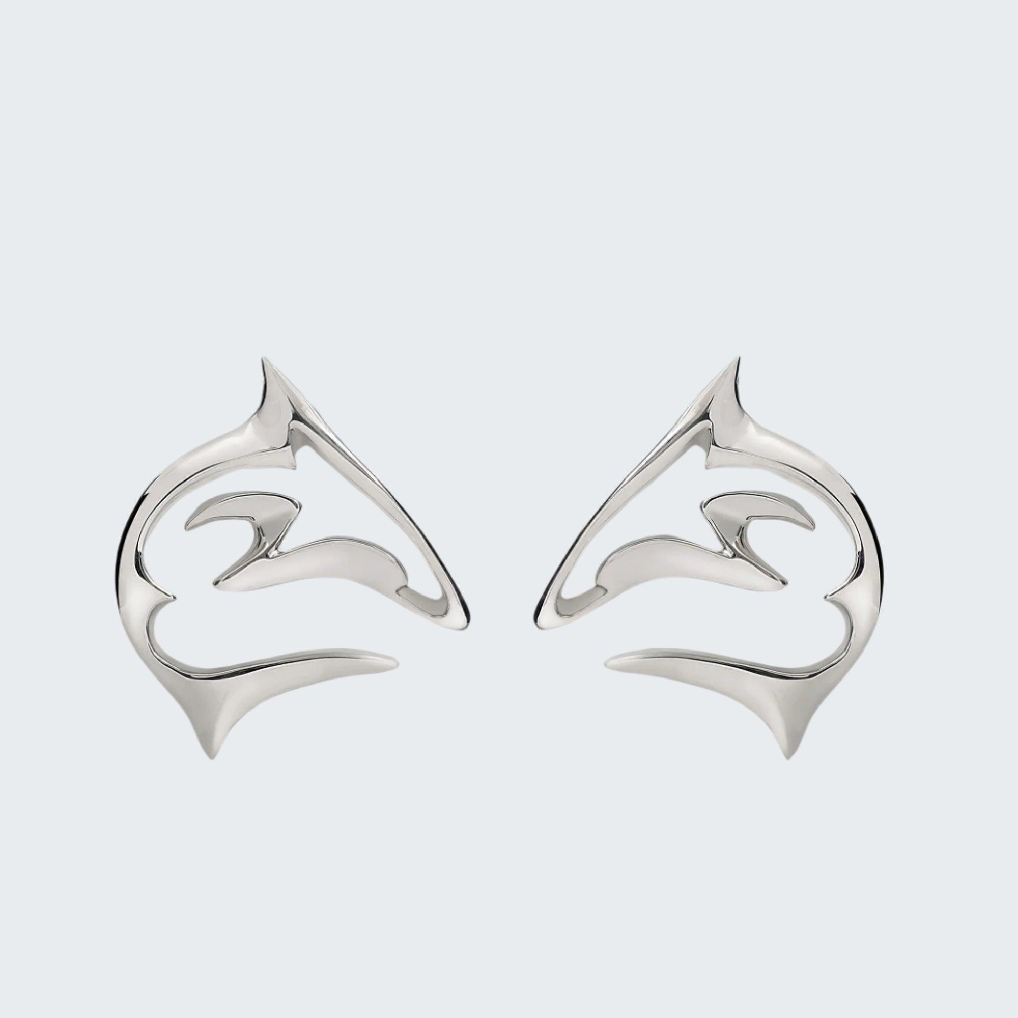 Silver dolphin-shaped earrings on a sandy beach with a blue sky background