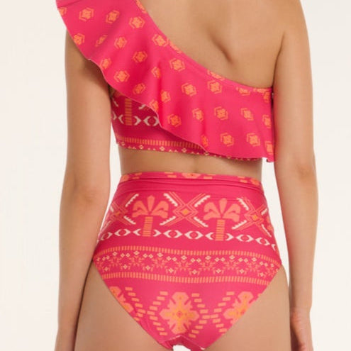 Woman wearing a pink patterned one-shoulder bikini set on a white background