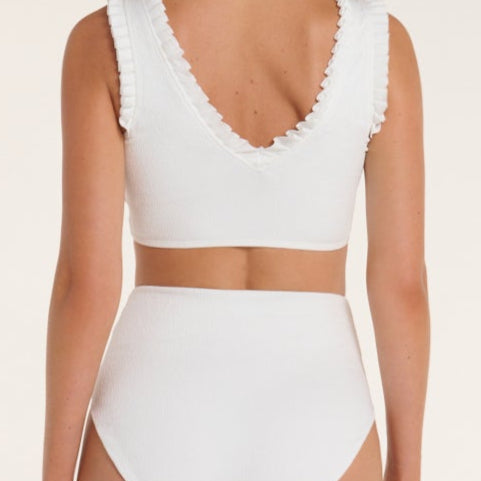 White bikini set with ruffled details on a beige background