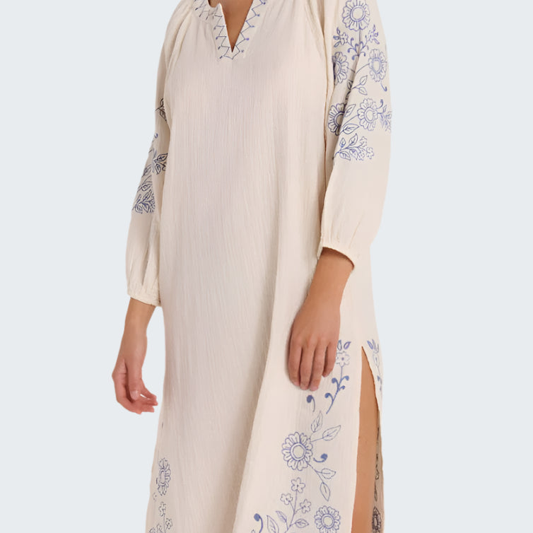Woman wearing a beige dress with floral embroidery on a white background