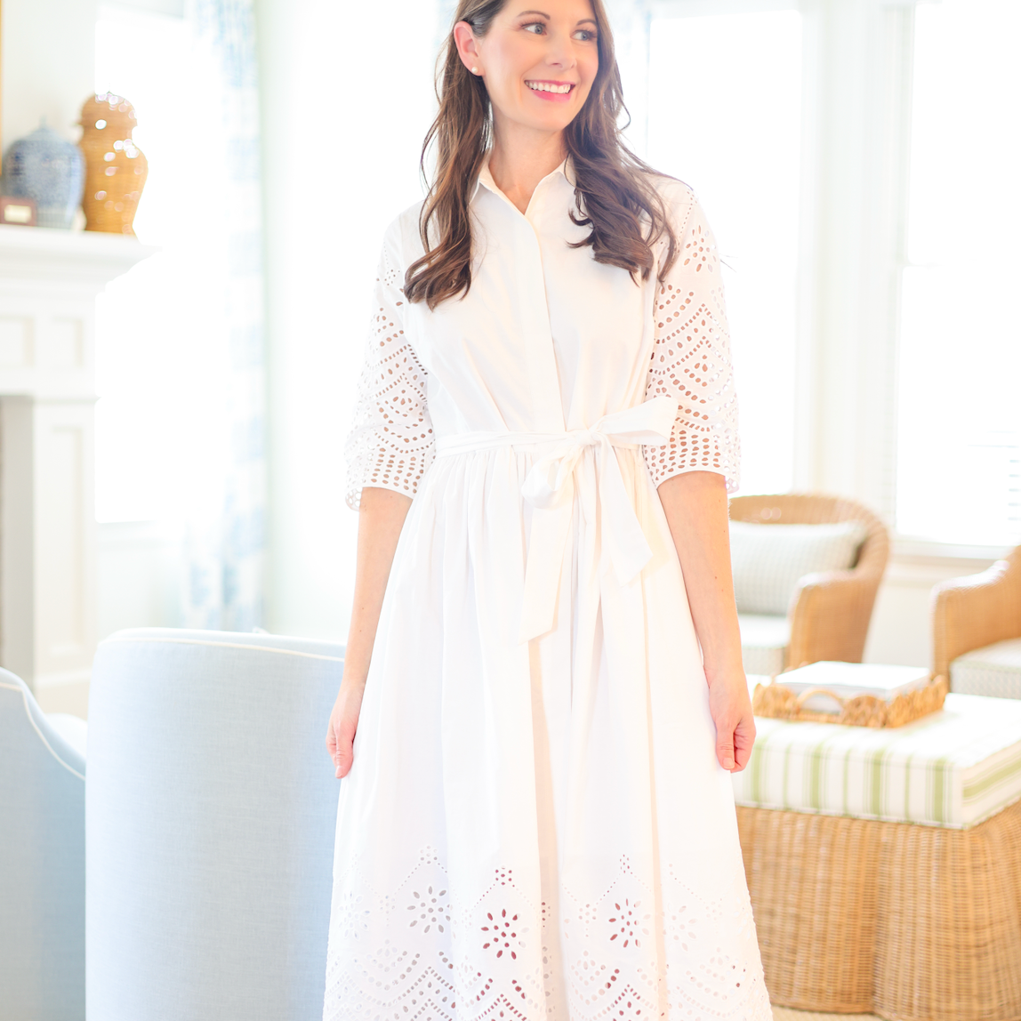 Woman wearing a white dress with lace details in a bright room.