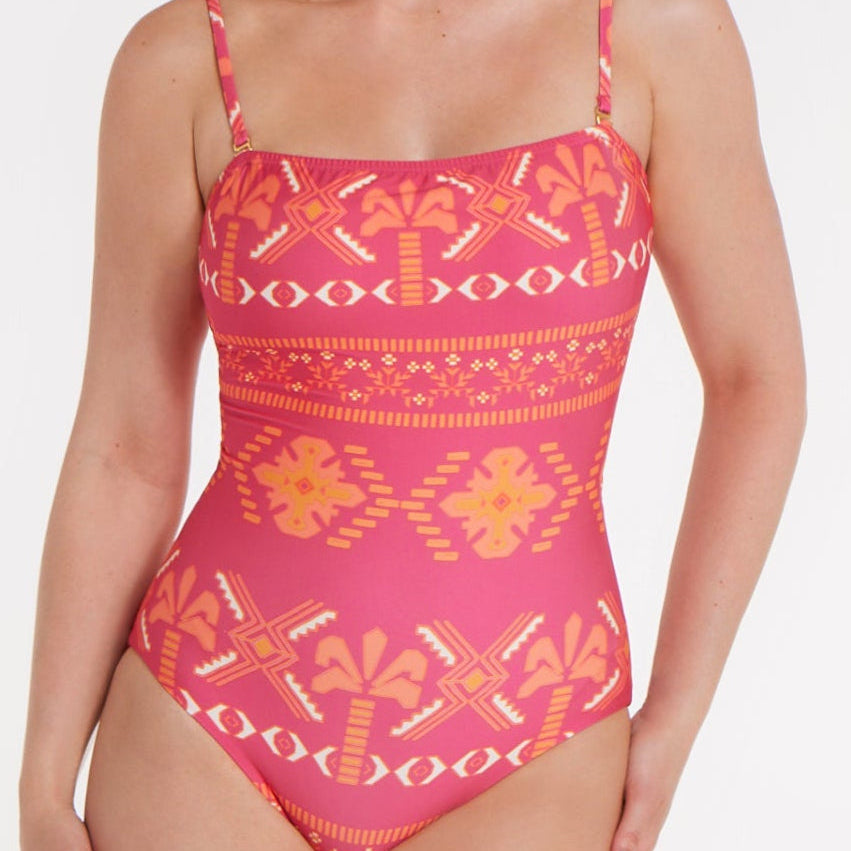 Woman wearing a pink and orange patterned swimsuit on a white background