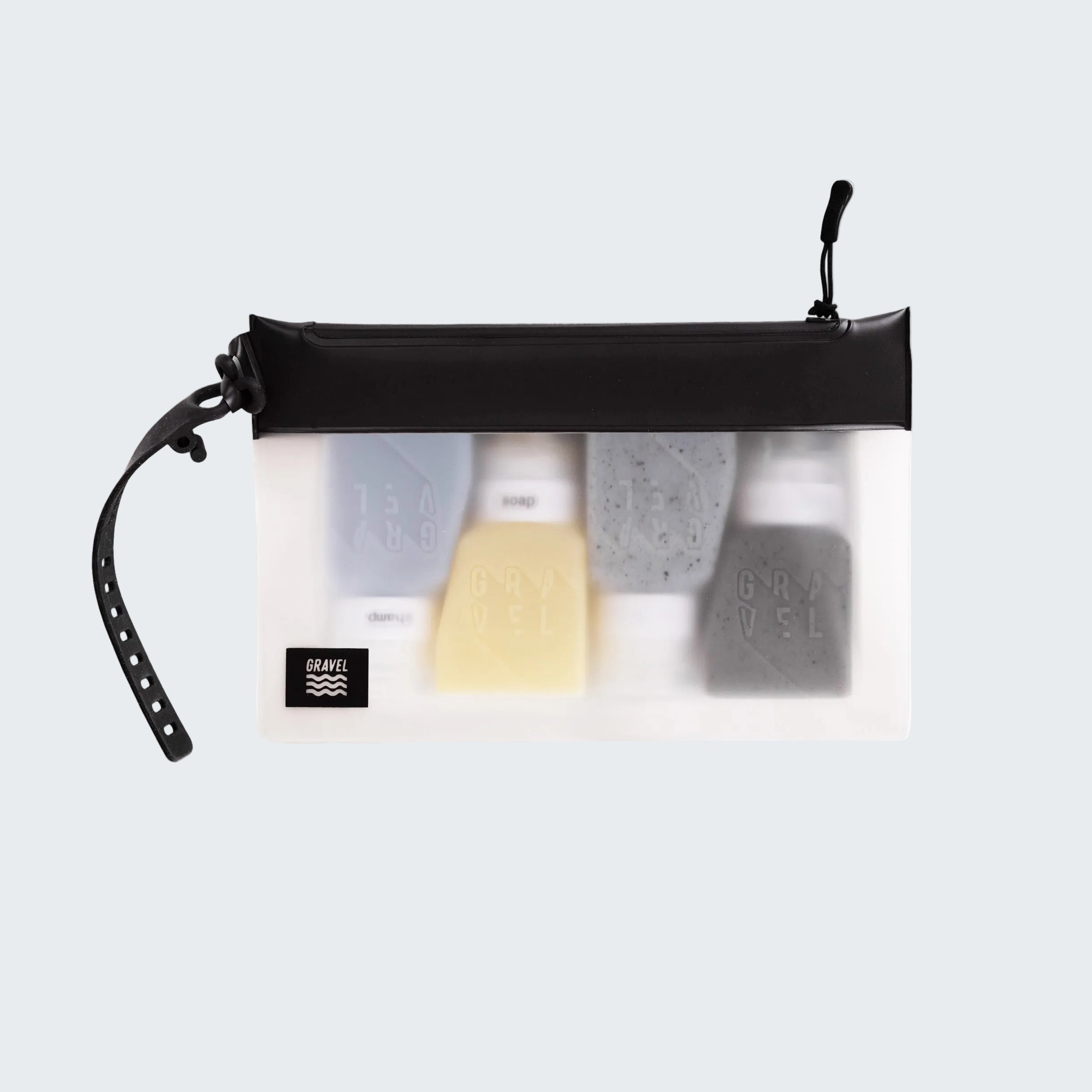 Clear travel pouch with black zipper containing various toiletries on a white background