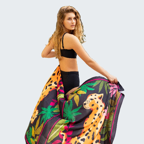 Woman holding a colorful towel with leopard print by a poolside