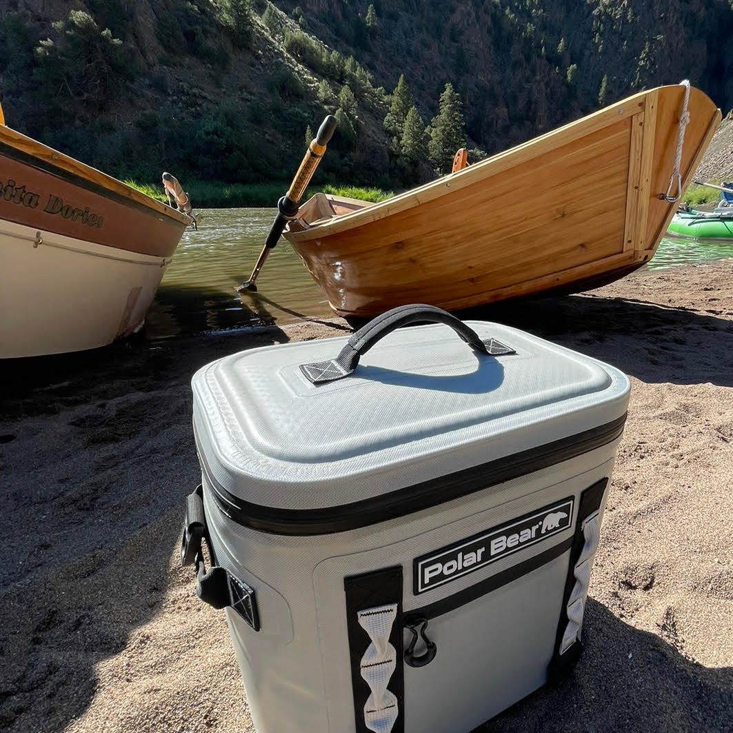 Polar Bear cooler on a sandy beach with wooden boats in the background