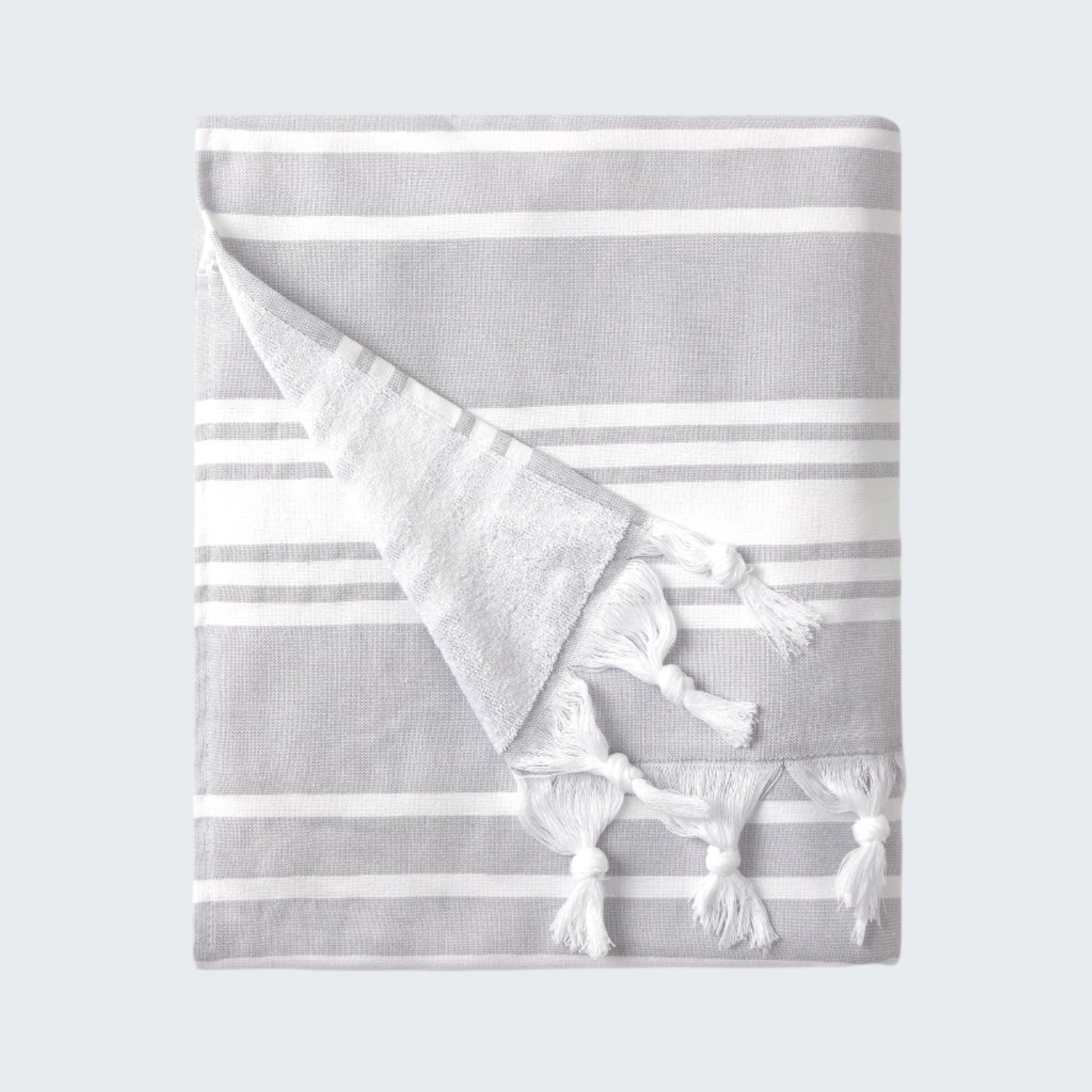 Folded gray and white striped towel with tassels on a white background