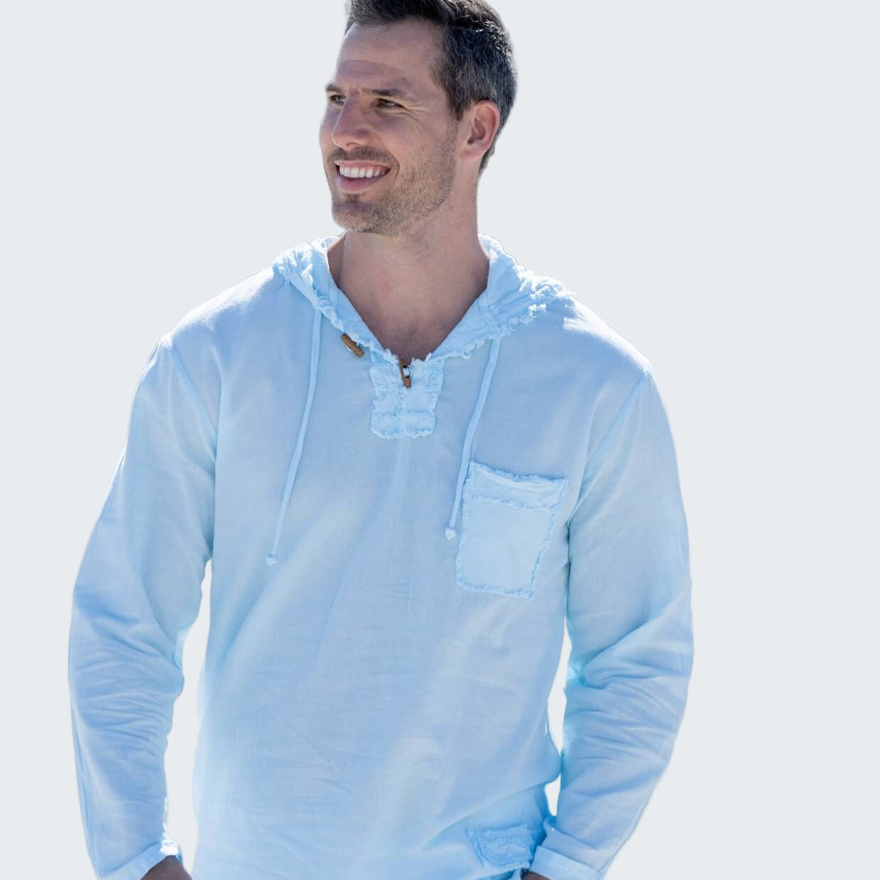 Man wearing a light blue hoodie with a palm tree-lined street in the background